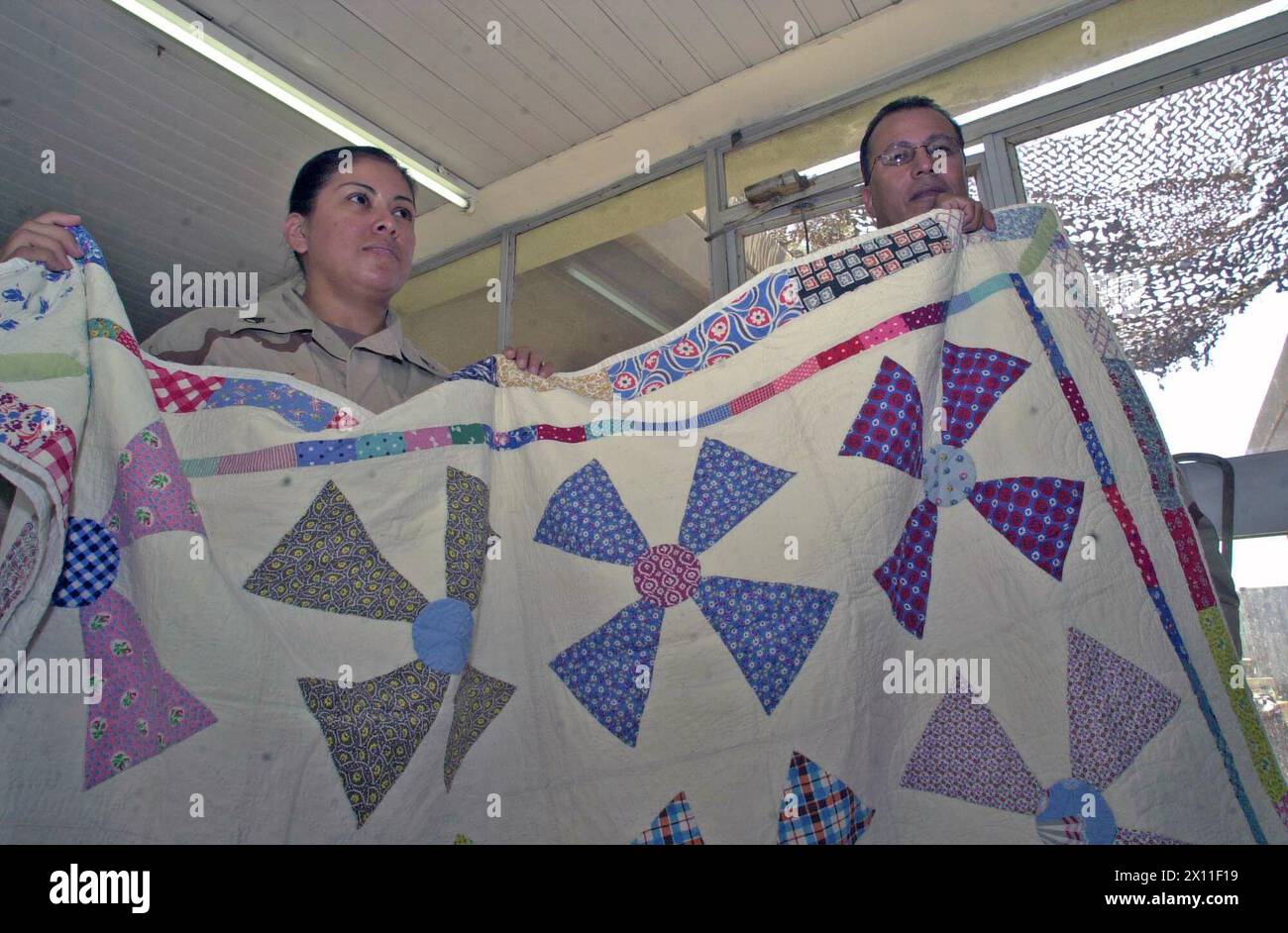 Staff-Sgt. Margie Chapman und Lt. Colonel Felipe Ibarra halten einen der Quilts, die von der Quiltorganisation Piecing for Peace gespendet wurden und den Übersetzern, die Zivilsachen bei LSA Anaconda und ihren Frauen CA assistieren, gespendet wurden. 2004 Stockfoto