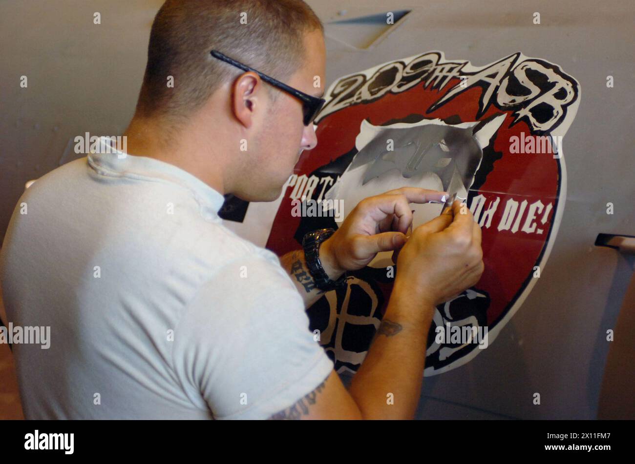 Ein Flugzeugbauer, zusammen mit der Bravo Company, 209th Aviation Support Battalion, 25th Combat Aviation Brigade, nutzt sein künstlerisches Talent, um dem L-29 Telfin Kriegsjäger ein 209th Symbol hinzuzufügen. Ort: Tikrit Iraq ca. Juli 2004 Stockfoto