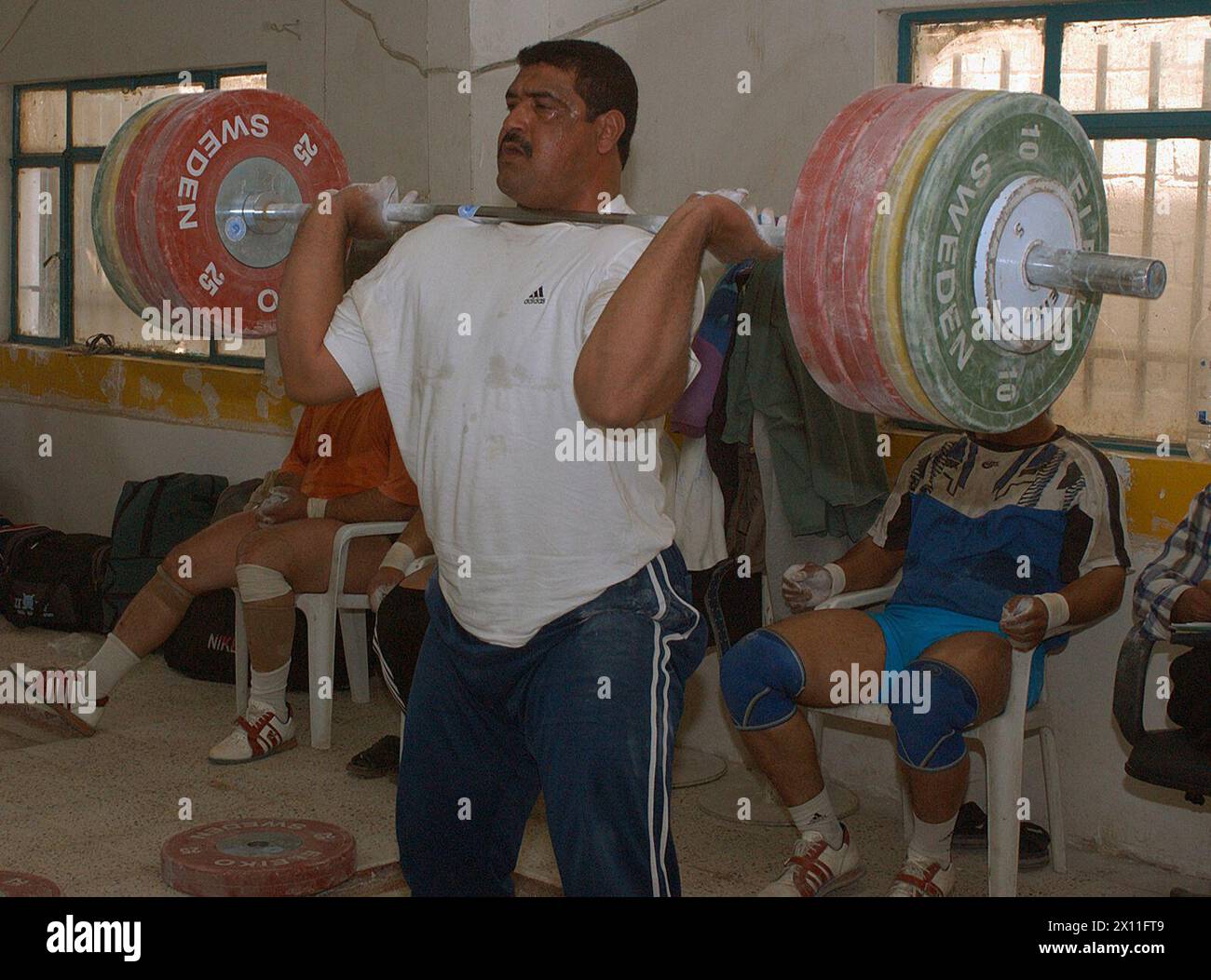 Harder, des irakischen Olympischen Gewichtheberteams, reinigt und ruckt 205 Kilo (451 Pfund) in der neuen Trainingsanlage im Gebiet Mustinsiria in Bagdad, 16. März 2004 Stockfoto