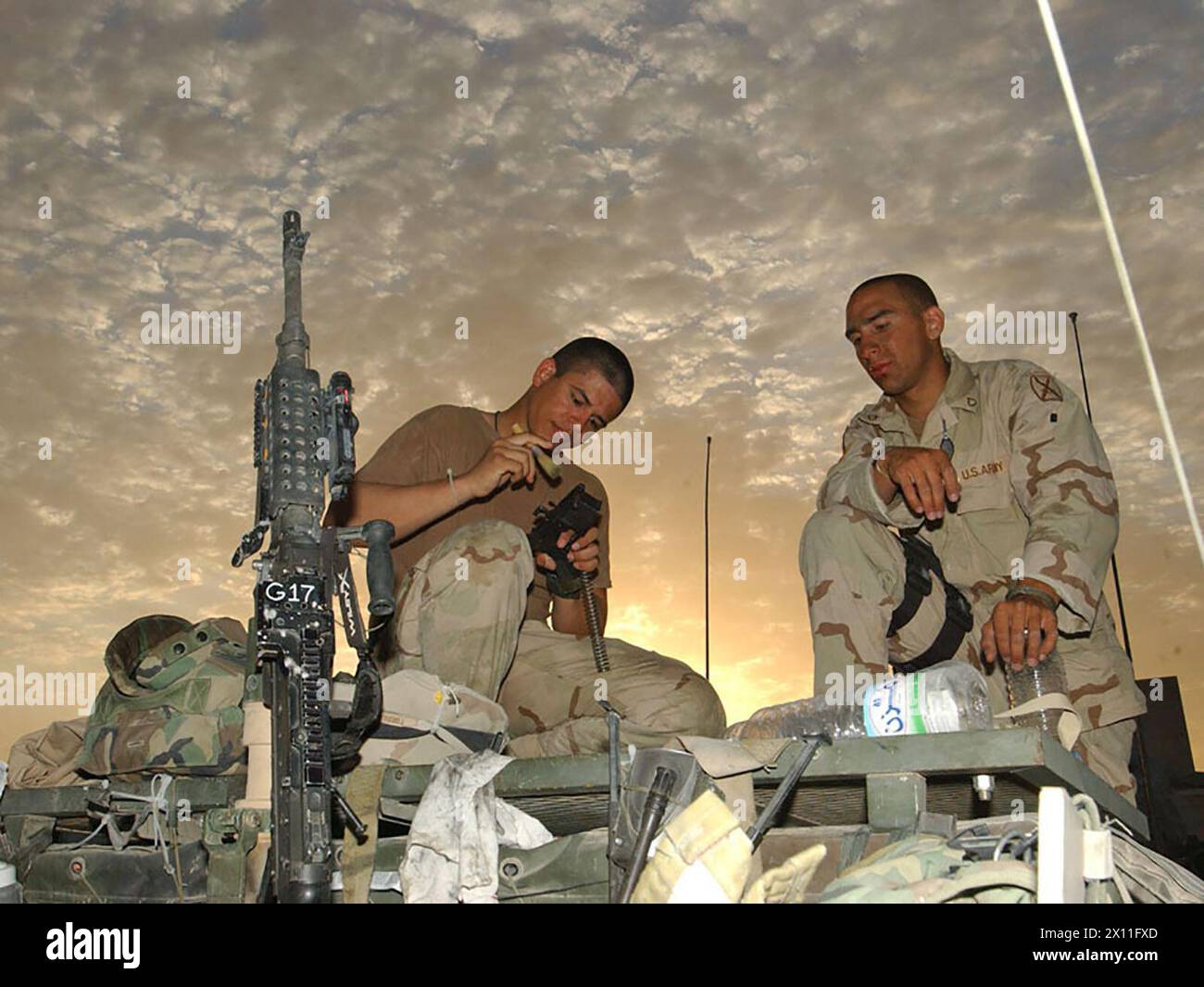 Elmer Garcia, ein Sanitäter, und Lionel Torres, ein Infanterie-Mann, beide mit dem 4. Bataillon, 31. Infanterieregiment, 10. Gebirgsdivision, reinigen die Waffen und bereiten sich auf die Rast im Kampfstützgebiet Scania vor, nach einem 12-stündigen Konvoi von Kuwait CA. Juli 2004 Stockfoto