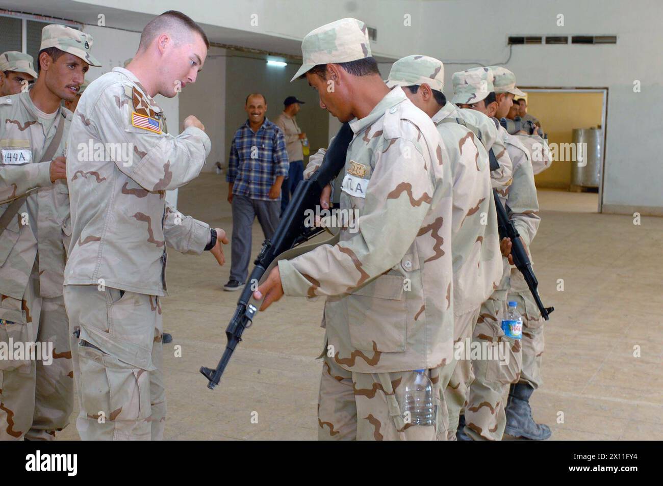 Darrin Nelson zeigt einem Soldaten der irakischen Nationalgarde, wie er seine Waffe beim Betreten und Freiräumen eines Raumes zeigt. Juli 2004 Stockfoto