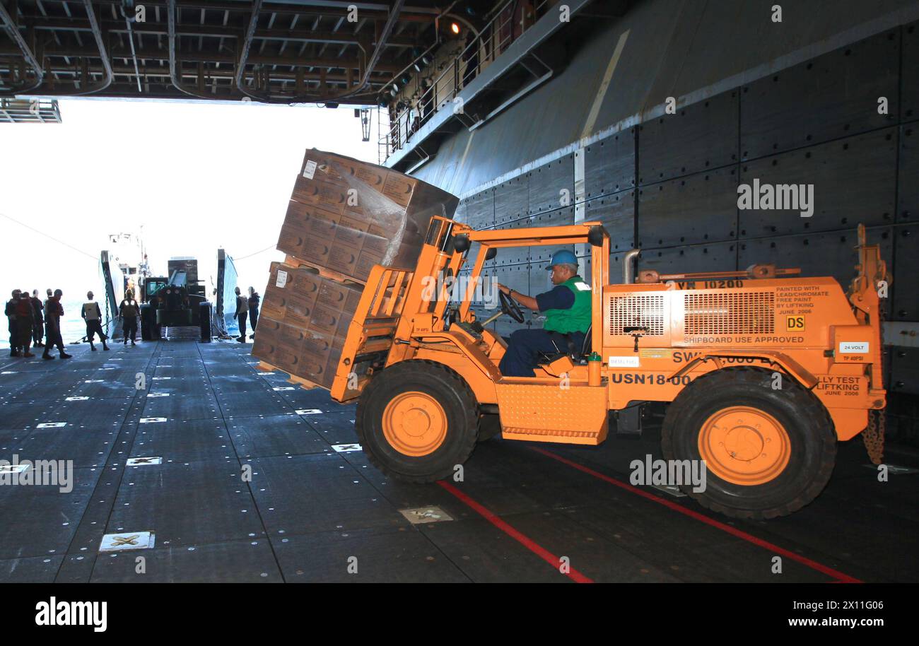 Ein Gabelstaplerfahrer der Navy mit der USS Bataan, einem amphibischen Angriffsschiff, bereitet sich darauf vor, Mahlzeiten auf ein Transportschiff zu laden, um die Marines am 24. Januar 2010 in Red Beach, Haiti, zu versorgen. Die 22. Marine Expeditionary Unit befindet sich an Bord der Schiffe der Bataan Amphibious Ready Mission nahe der Insel Haiti, um humanitäre Hilfe und Katastrophenhilfe nach dem verheerenden Erdbeben, das das Land am 12. Januar heimsuchte, zu leisten. Stockfoto