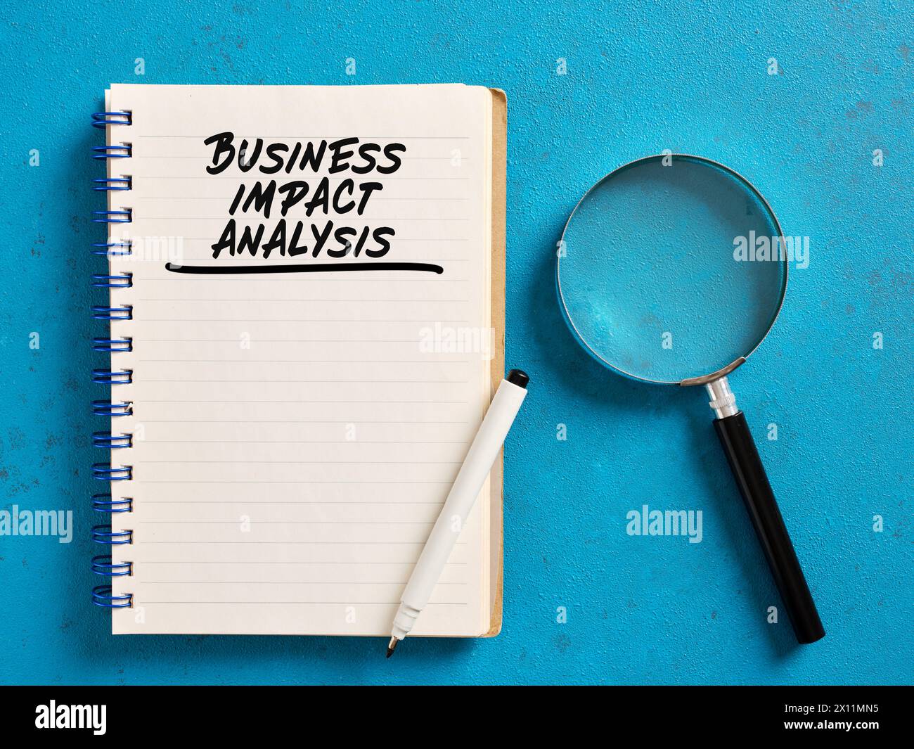Handgeschriebene Analyse der geschäftlichen Auswirkungen auf einem Notebook mit einer Lupe. Geschäftsstrategie und Planungskonzept. Stockfoto