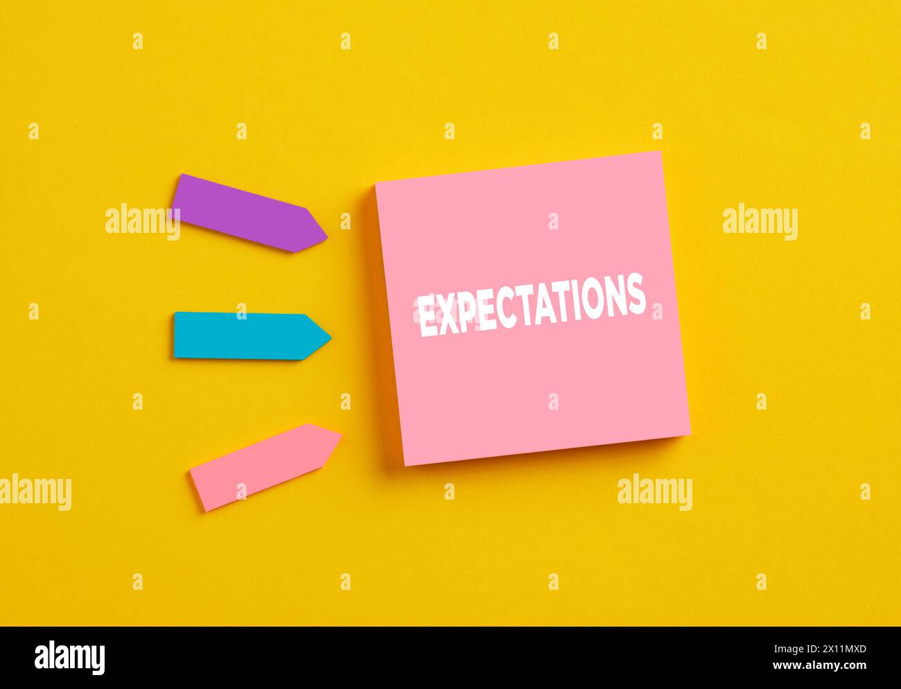 Erwartungen in Wirtschaft oder Bildung. Das Wort Erwartungen auf rosa Notizpapier. Stockfoto