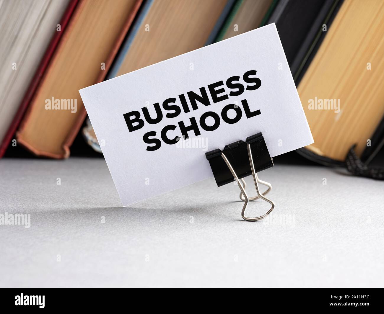Das Wort Business School steht auf einer Visitenkarte mit Buchhintergrund. Wirtschaftsschulbildungskonzept. Stockfoto