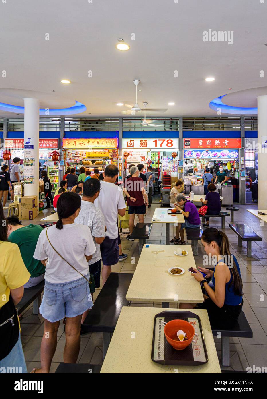 Die Leute stehen in einem geschäftigen Hawker Centre am Tiong Bahru Markt im Tiong Bahru Estate, Singapur Stockfoto