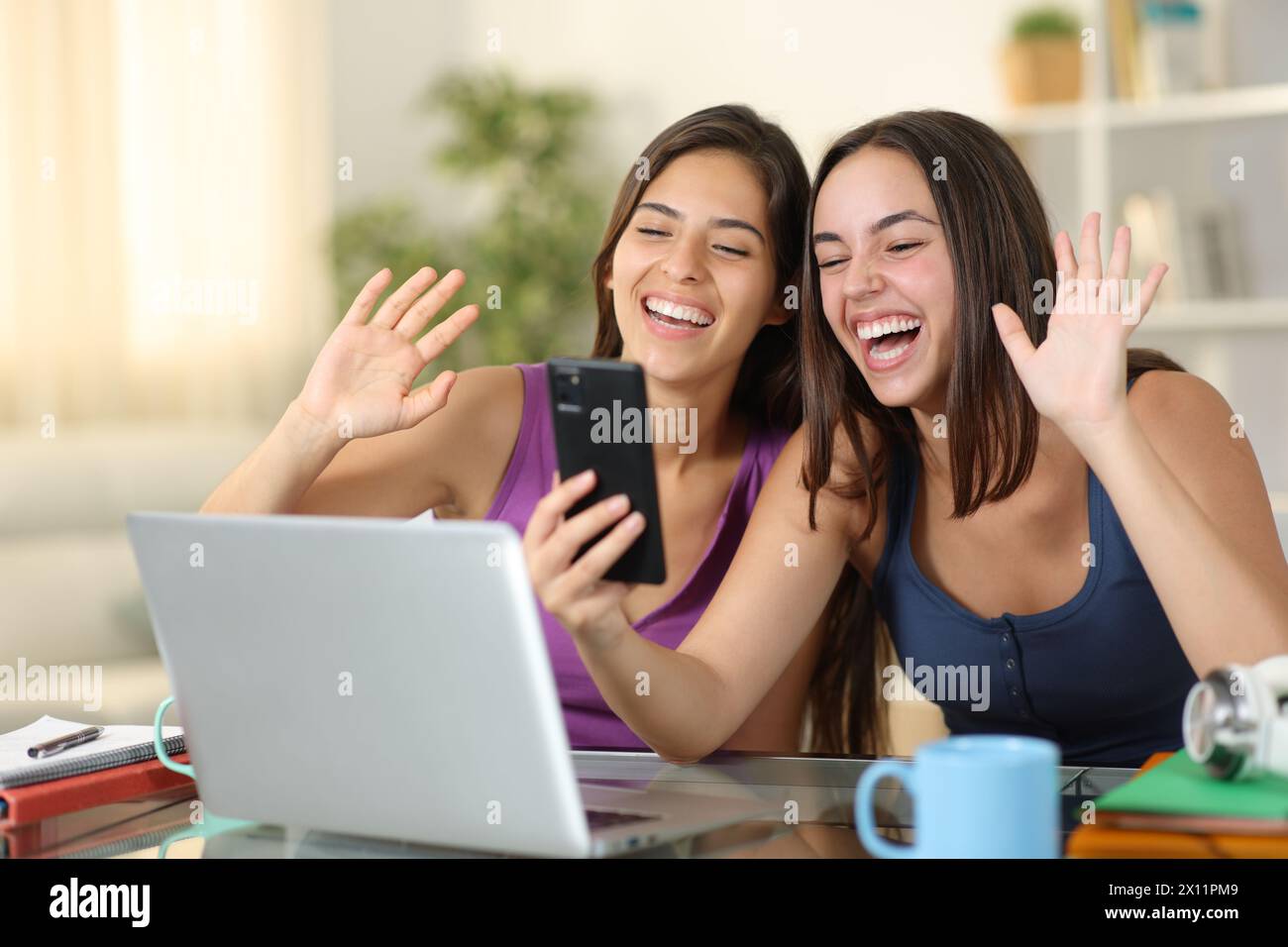 Zwei glückliche Schüler, die zu Hause telefonieren Stockfoto