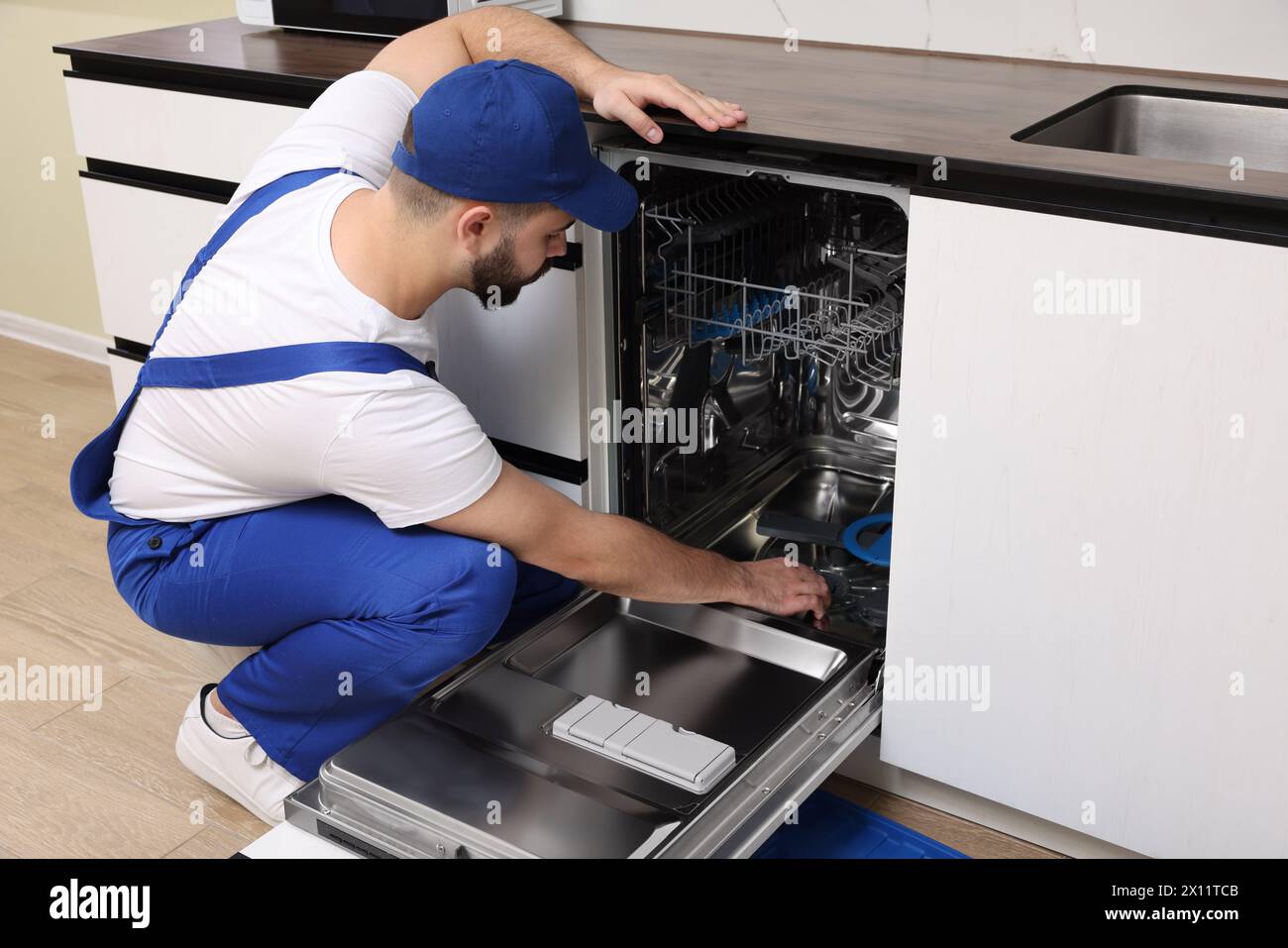 Service repariert und untersucht Geschirrspüler in der Küche Stockfoto