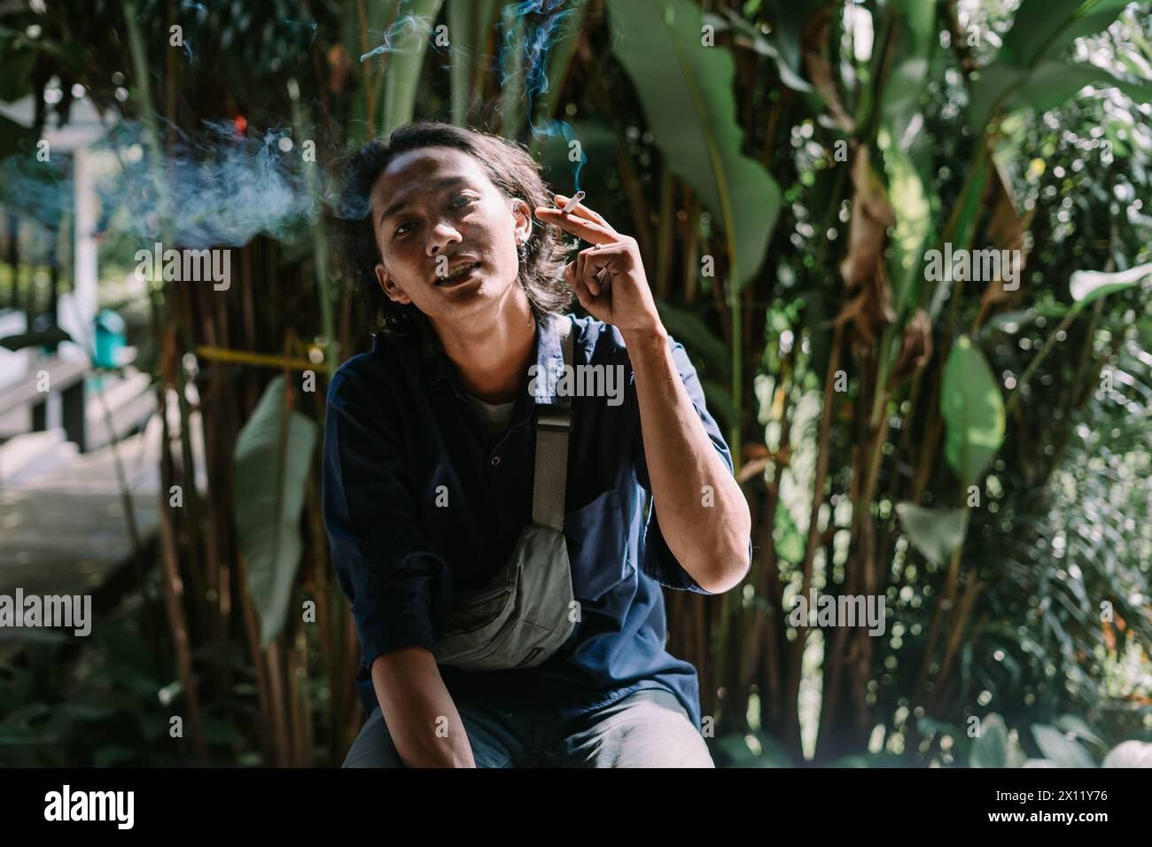 Ein Mann, der seine Zigarette in einem Bereich von ​​dense-Bäumen verbrannt hat Stockfoto