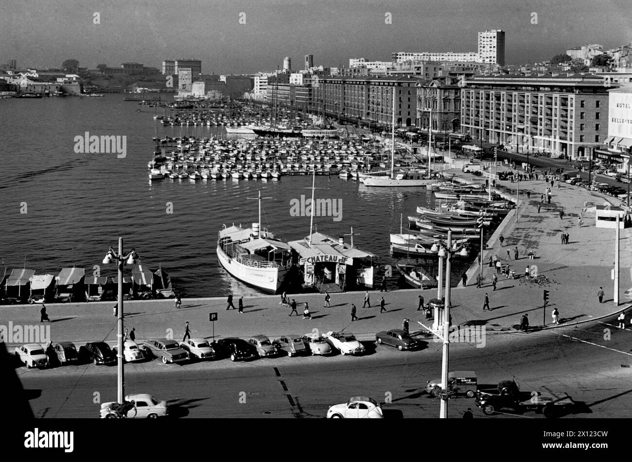 Blick aus der Vogelperspektive, Hochwinkelblick oder historischer Blick auf den Alten Hafen oder Vieux Port, mit Oldtimer aus den 1950er bis 1960er Jahren, geparkt am Quayside Marseille oder Marseills France. Historisches oder Vintage-Schwarzweiß- oder Schwarzweißbild c1960. Stockfoto