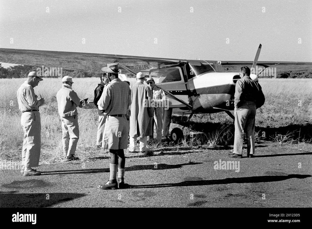 Passagiere bereiten sich auf den Einstieg in das Cessna 170 Light Airplane, Flugzeug oder Flugzeug (hergestellt zwischen 1948 und 1956) auf dem Flugplatz oder Flughafen von Fort Dauphin Madagaskar vor. Vintage- oder Historic Schwarzweiß- oder Schwarzweißbild c1960. Stockfoto