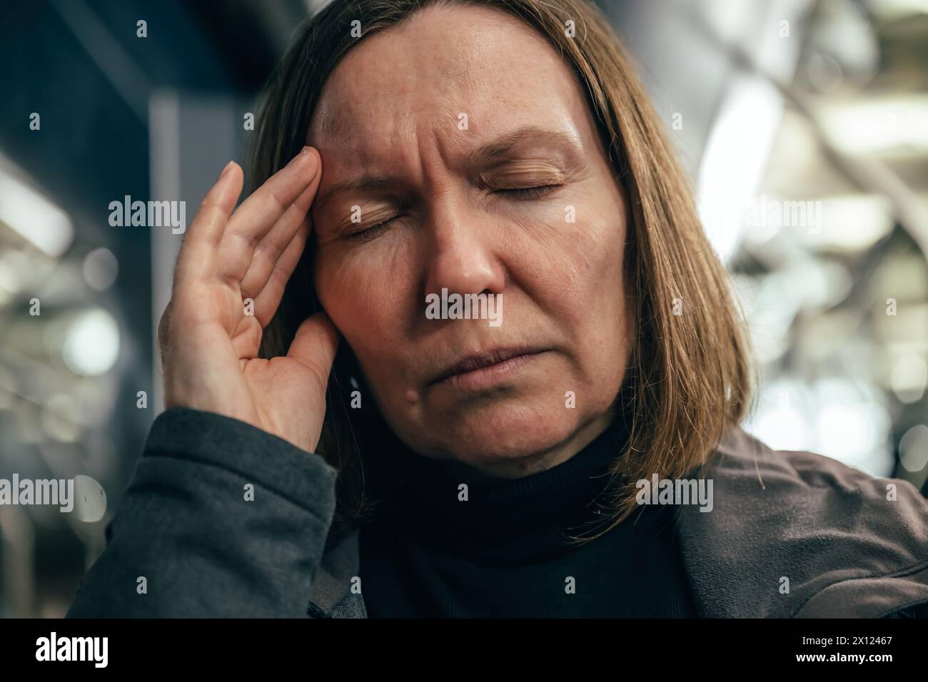 Erwachsene kaukasische Frau mit schweren Migräne-Kopfschmerzen, die nachts im Bus mit öffentlichen Verkehrsmitteln fährt, selektiver Fokus Stockfoto
