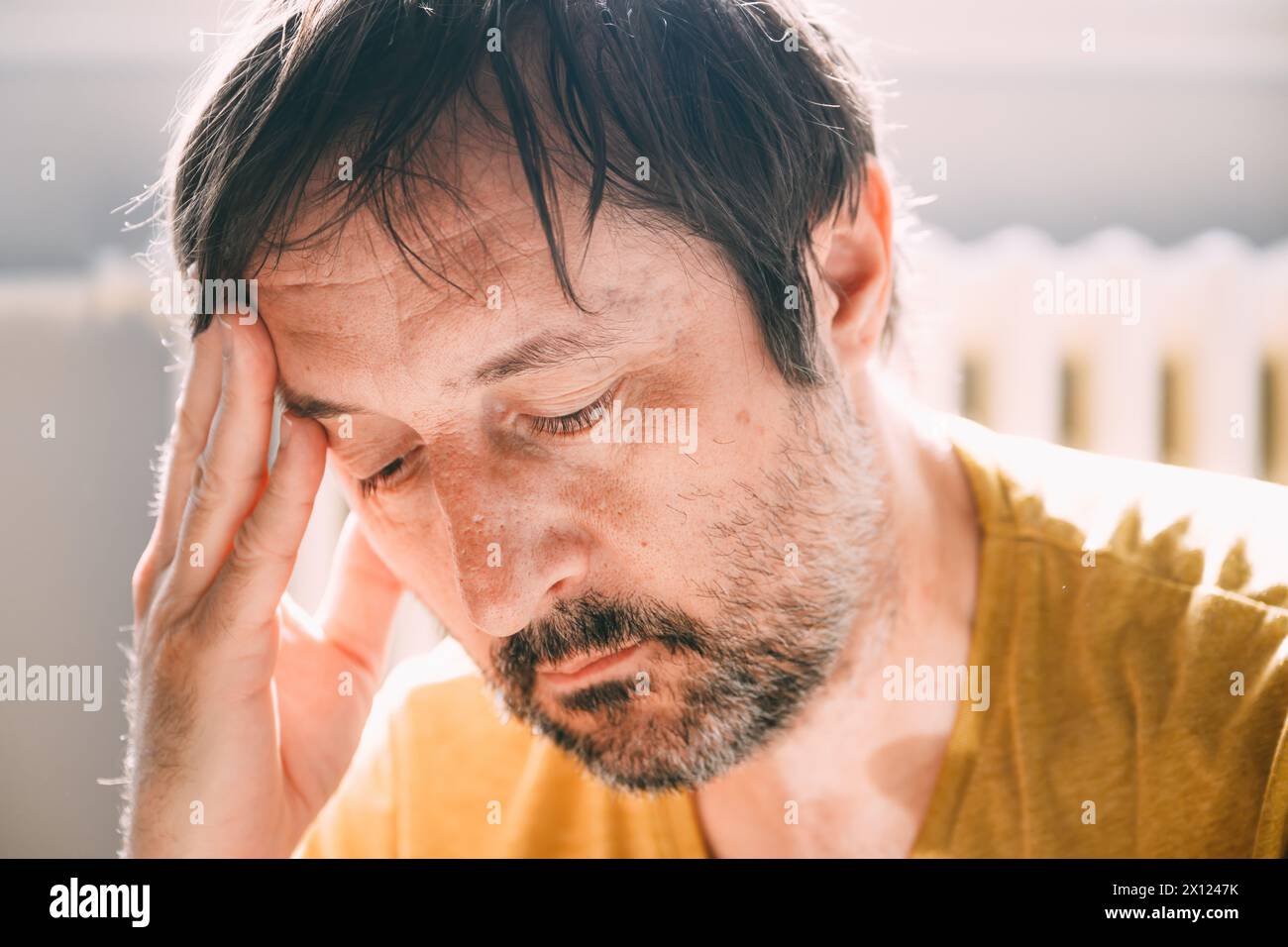 Reue-Konzept, bedauernswerter ungepflegter Mann zu Hause im Wohnzimmer, beleuchtet von der Morgensonne, selektiver Fokus Stockfoto