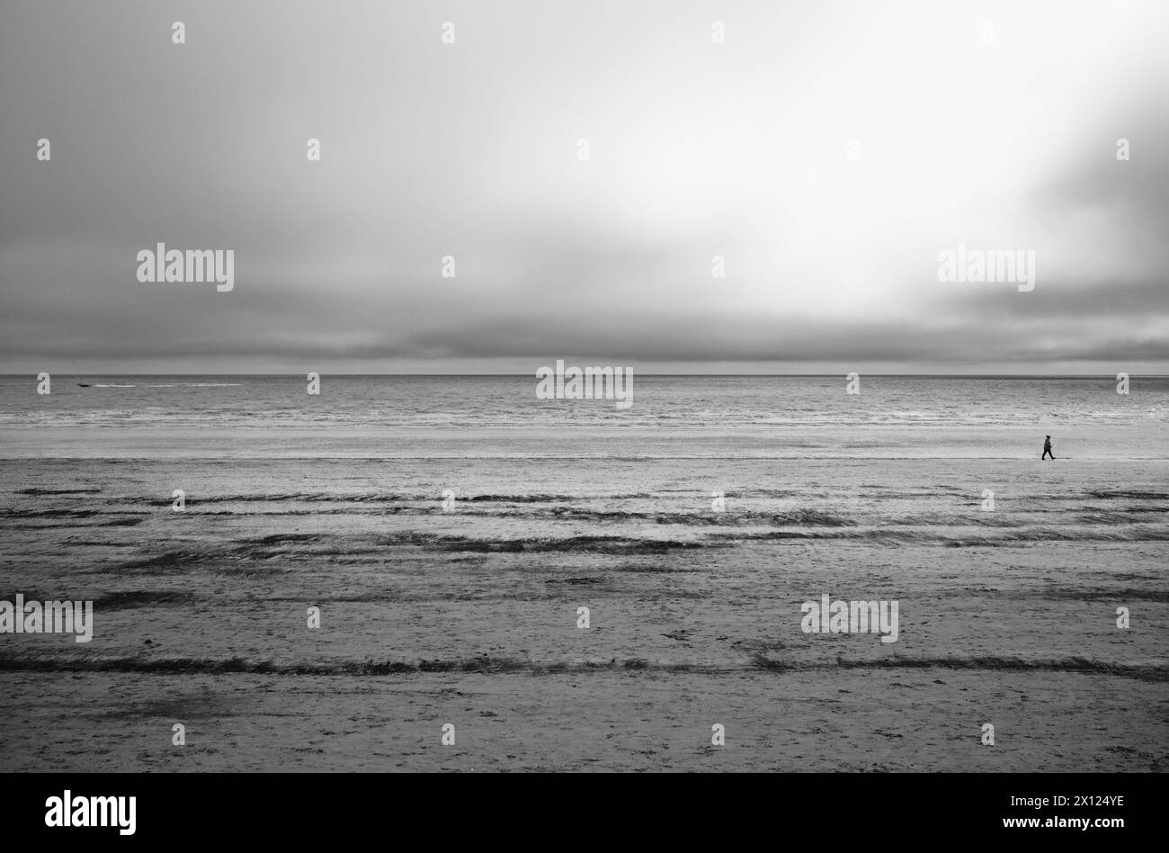 Ein einsamer Wanderer am Bridlington Beach bei Ebbe in Schwarz-weiß Stockfoto
