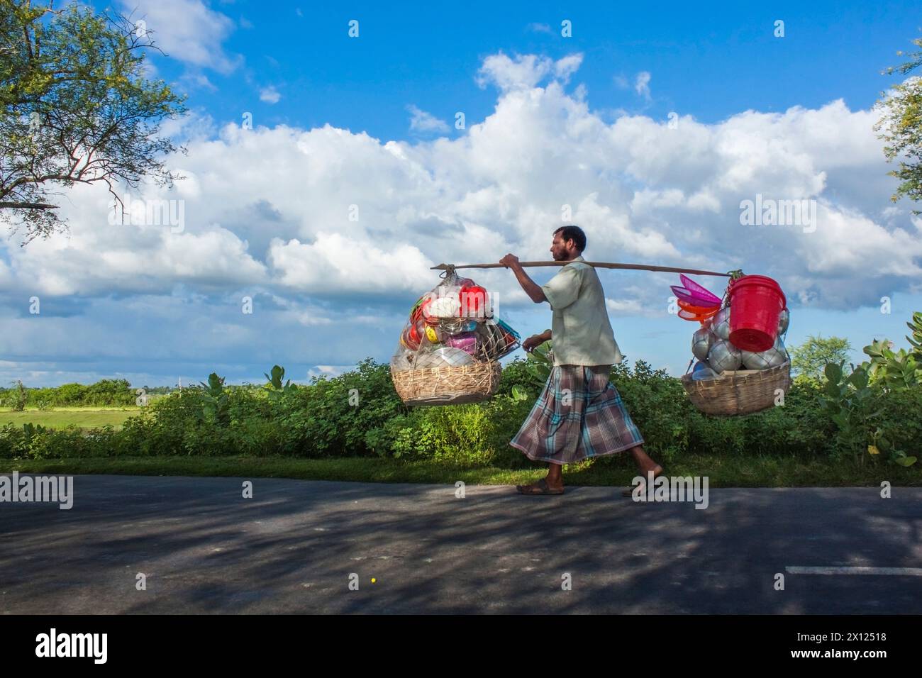 Dieser Mann geht in verschiedene Dörfer und verkauft Plastikgegenstände. Stockfoto