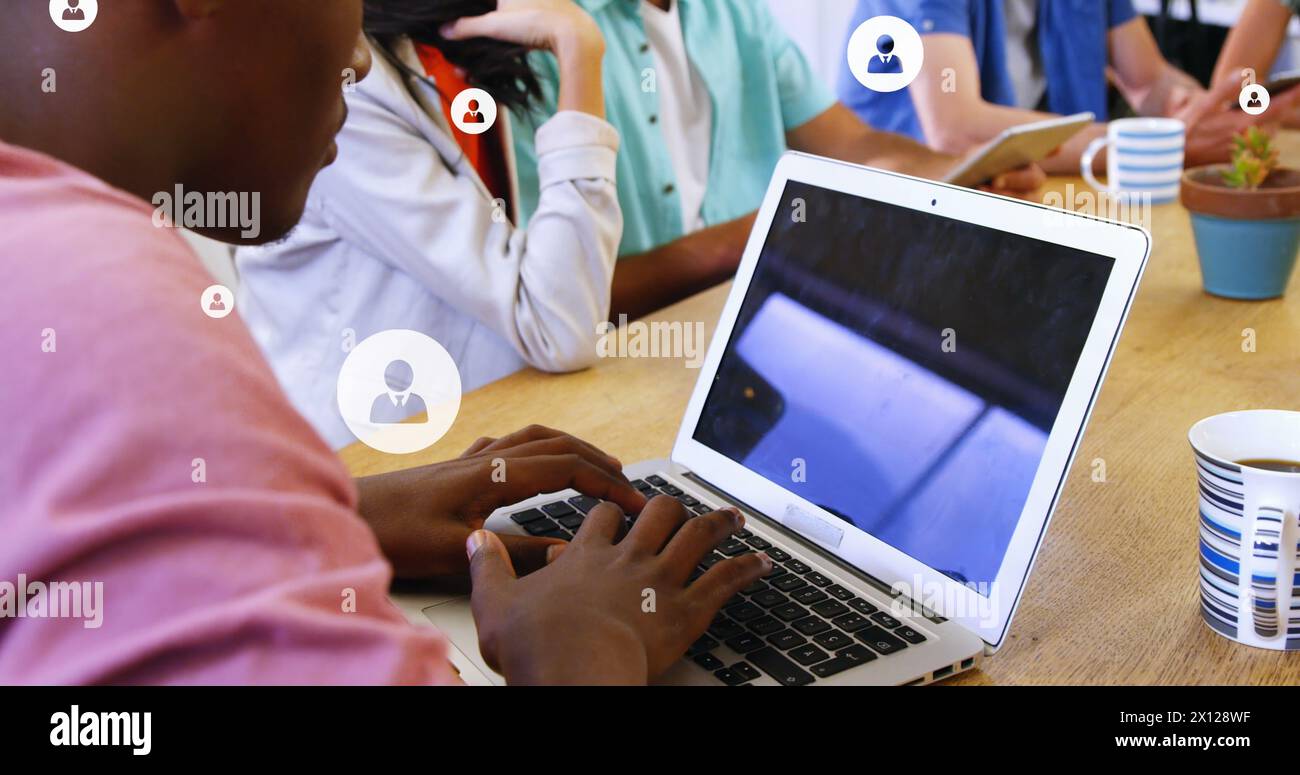 Bild mehrerer Profilsymbole über verschiedenen Kollegen, die über ein Notebook diskutieren und arbeiten Stockfoto