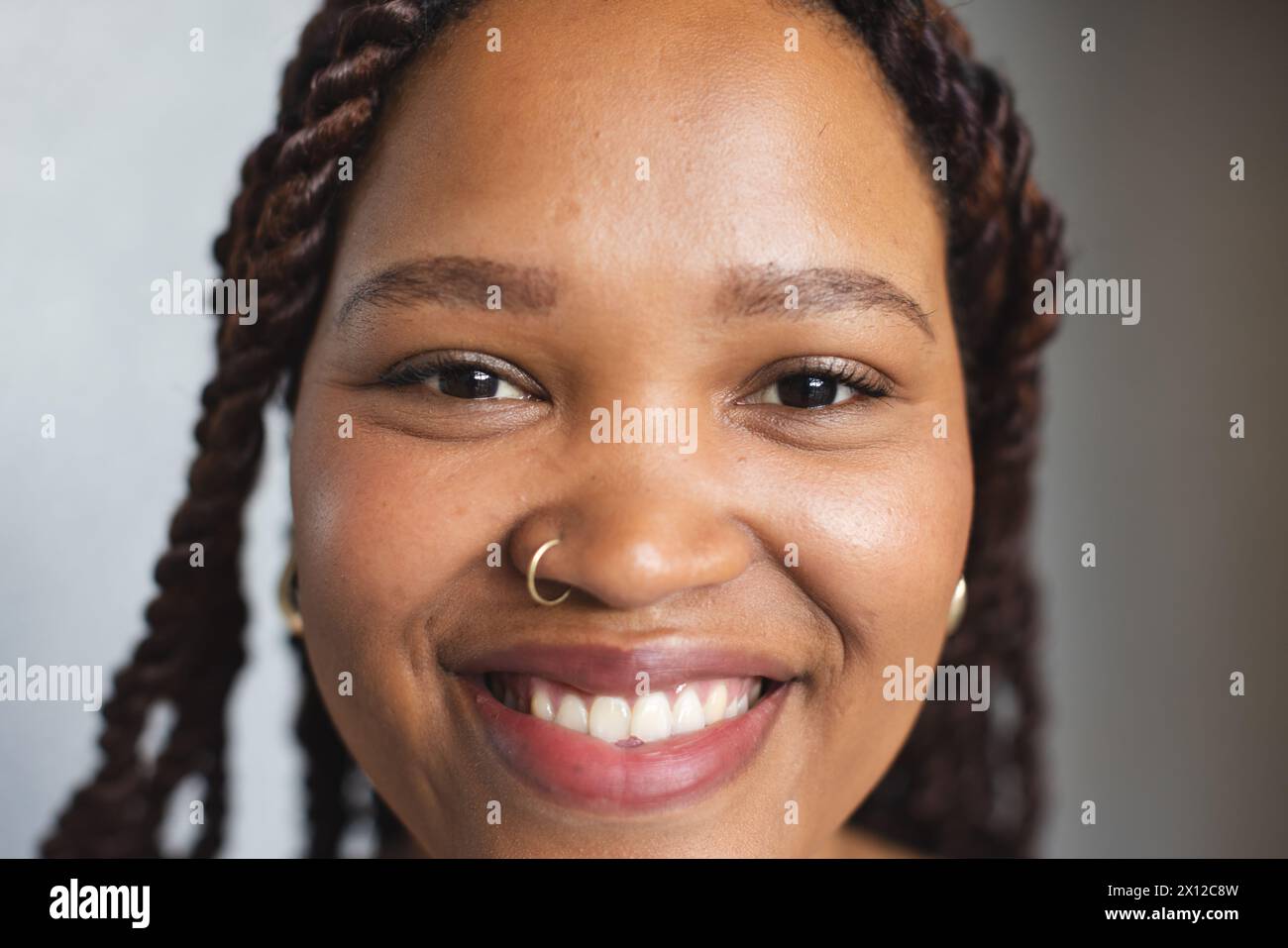 Eine junge Frau mit geflochtenen Haaren lächelt in einem modernen Geschäftsbüro in die Kamera Stockfoto