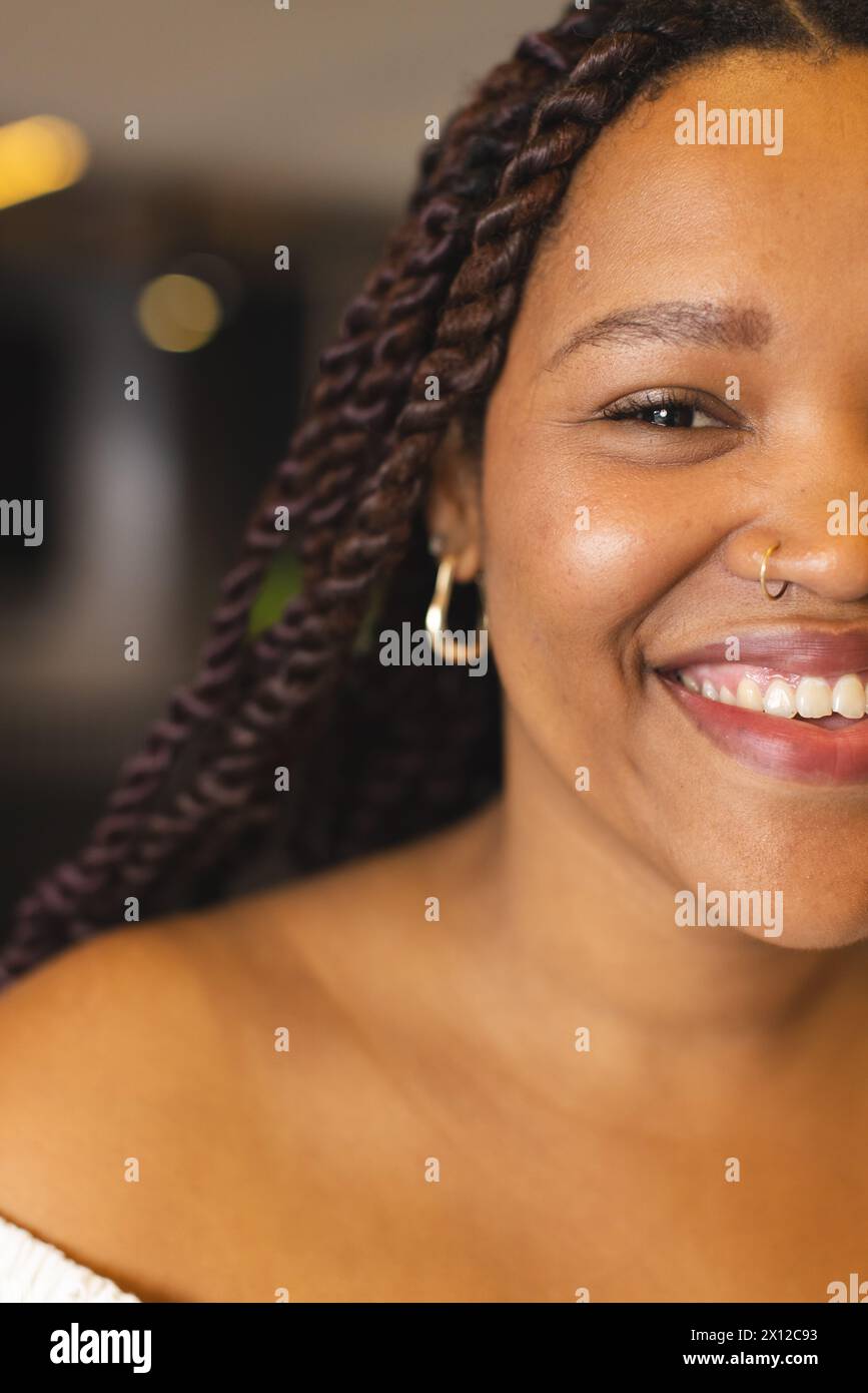 Eine junge Frau, die eine Rasse hat, lächelt, trägt Nasenring und Creolen, in einem modernen Geschäftsbüro Stockfoto