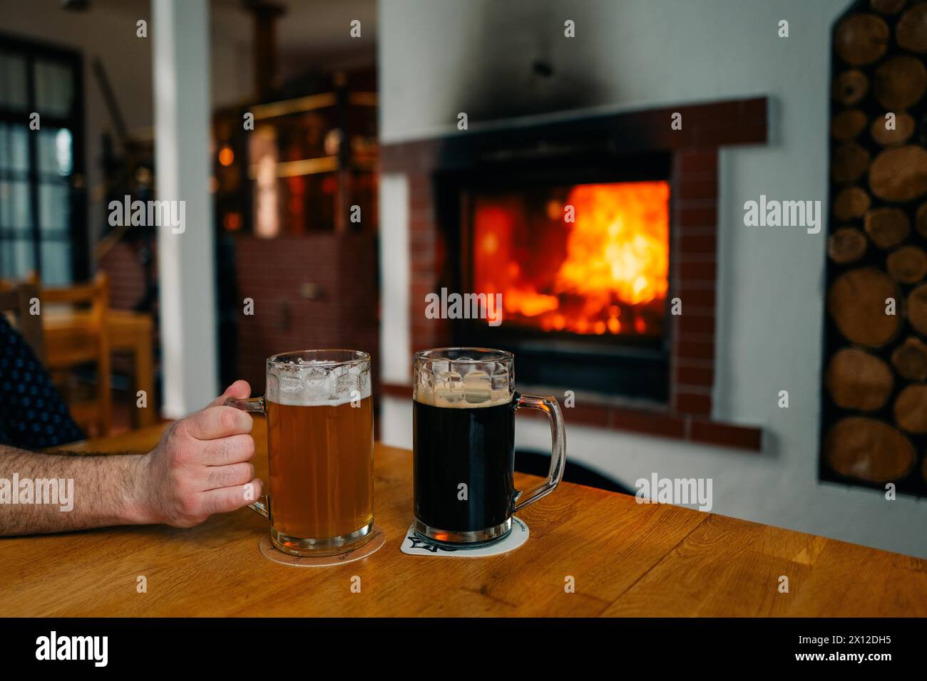 Zwei Gläser Bier, hell und dunkel, in einem Pub am Kamin Stockfoto