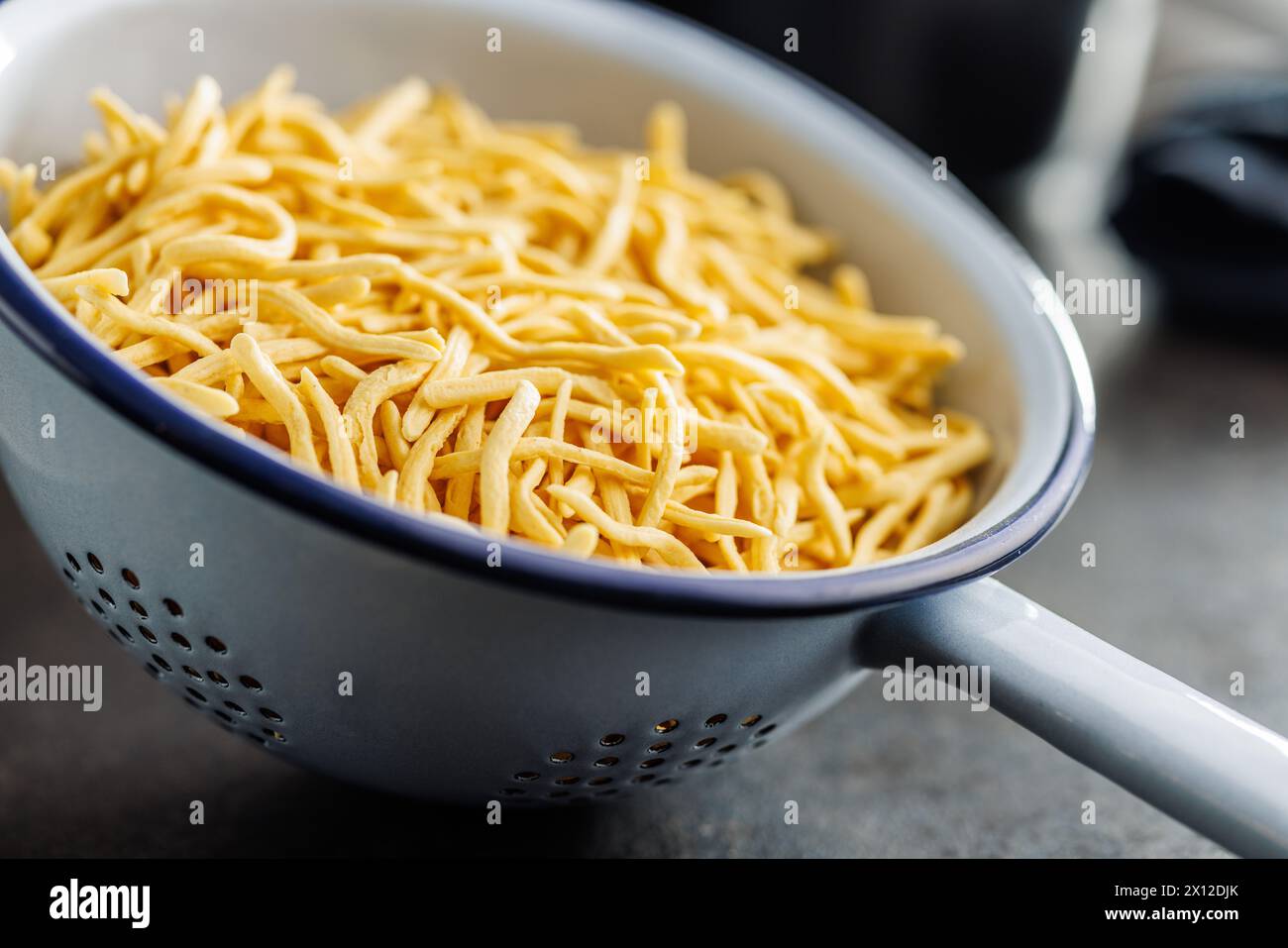 Ungekochte Spätzle Nudeln im Sieb auf einem Küchentisch. Stockfoto