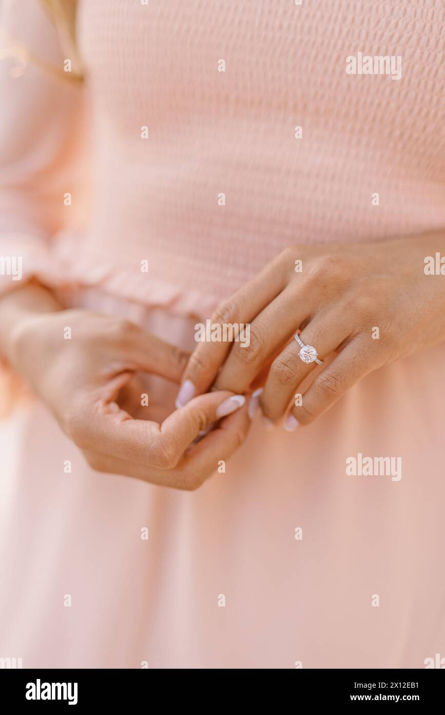 Runder Verlobungsring an der Hand der Frau in rosa Kleid Stockfoto