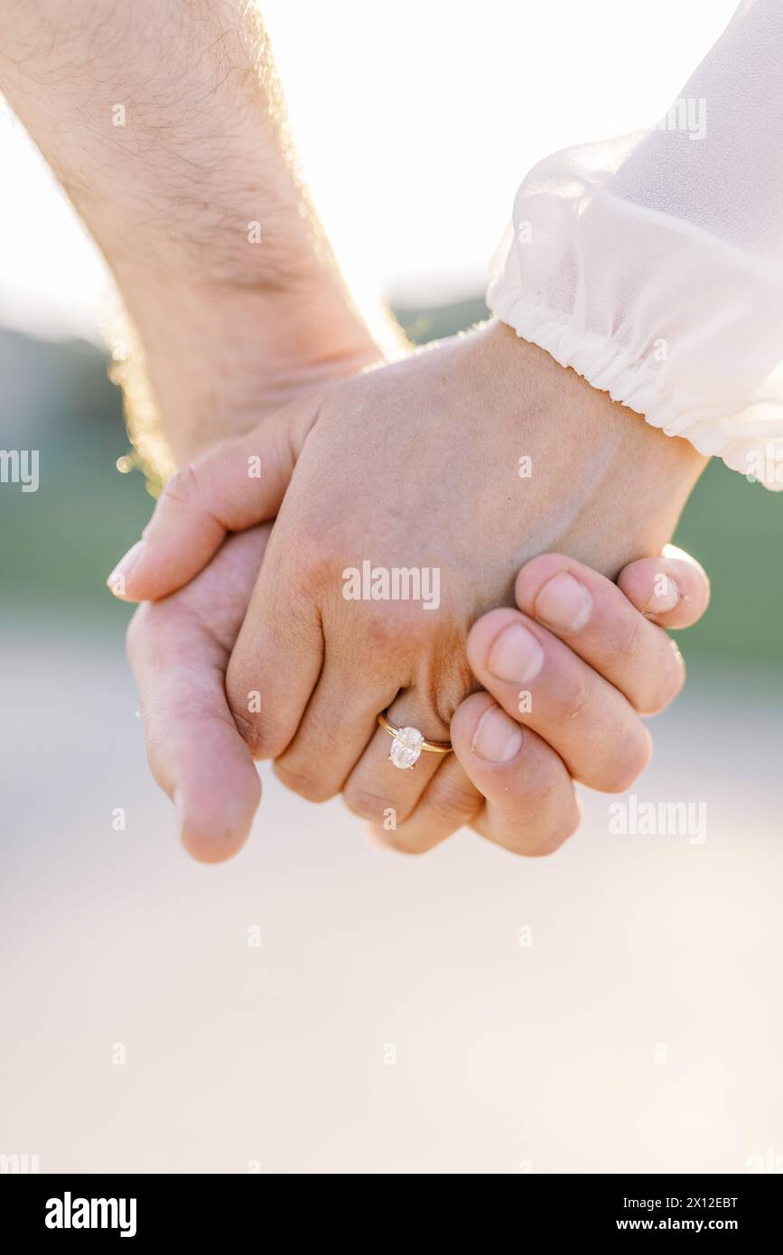 Ineinander verflochtene Hände mit ovalem Diamant-Einpressring Stockfoto