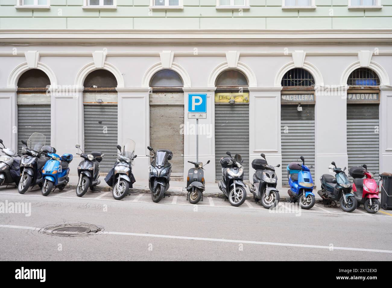 Eine Reihe geparkter Motorroller vor historischer Fasadescooter Parkplatz, Stadt, Verkehr, Parkplatz, Vespa, Zweiräder, Straße, urbane Mobilität, Architekt Stockfoto