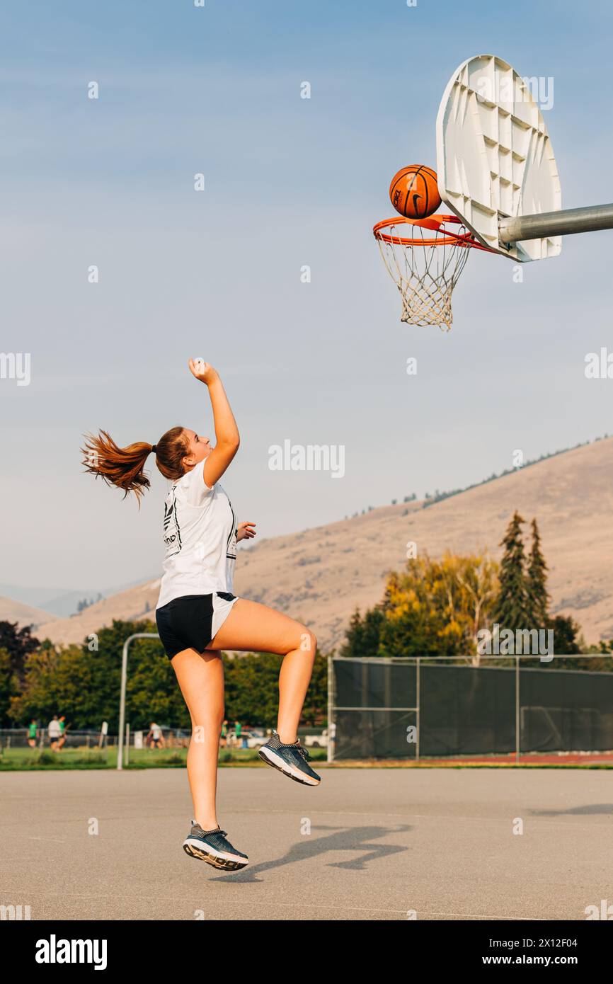 Mädchen mit Ponyschwanz, das in der Luft springt und Basketball spielt Stockfoto