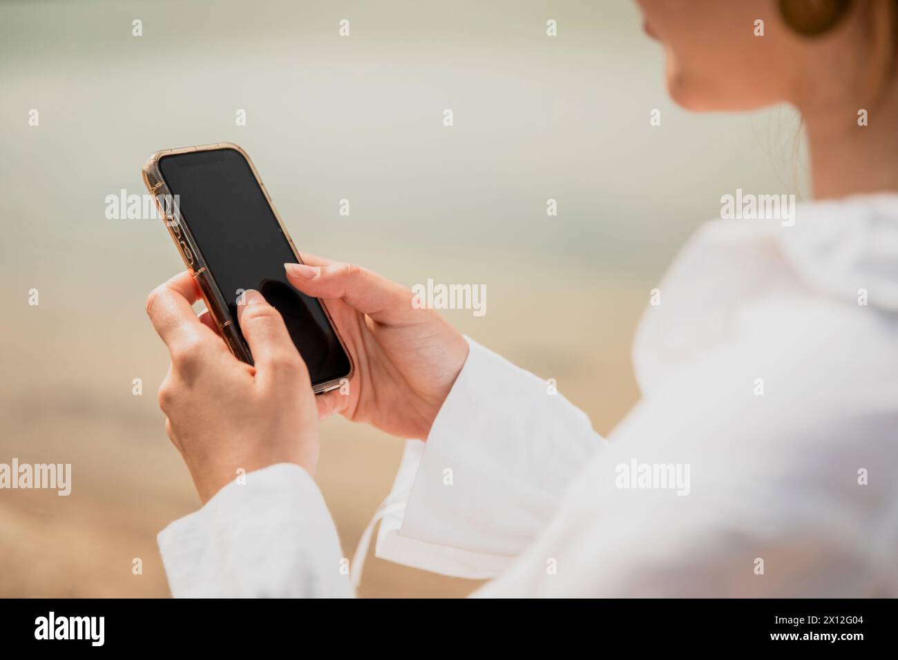 Nahaufnahme eines Mädchens Hände, die auf ihrem Smartphone neben einem See tippen Stockfoto