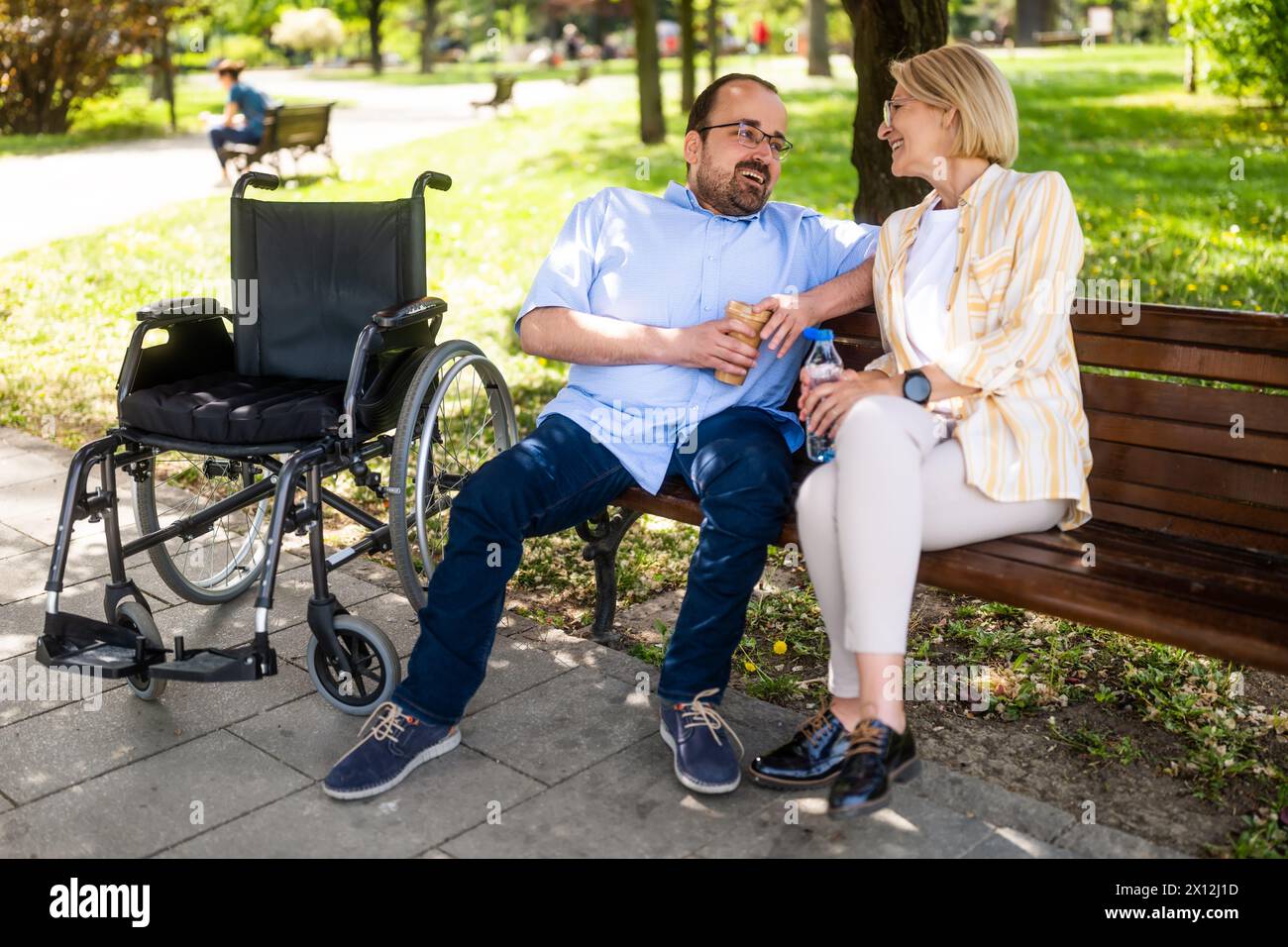 Ein Mann im Rollstuhl verbringt Zeit mit seiner Mutter im Park. Stockfoto