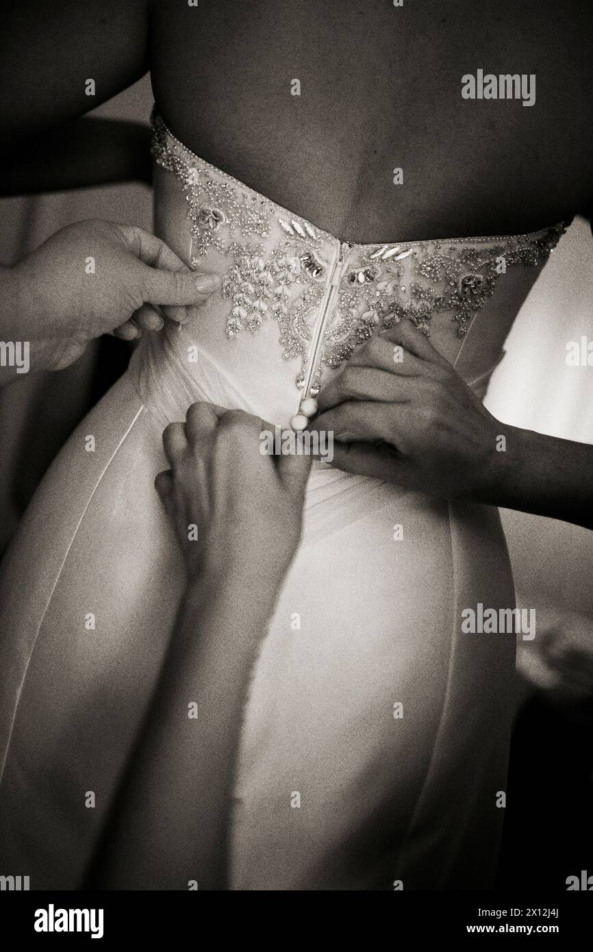 Braut zieht sich mit helfenden Händen an, schwarz und weiß Stockfoto