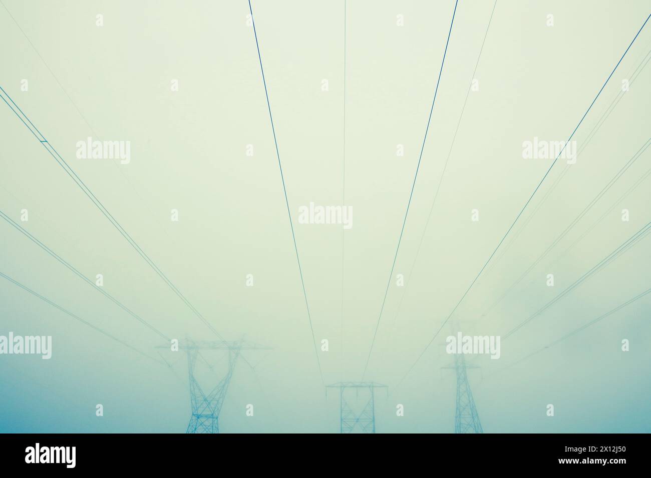 Stromleitungen und Türme im Nebel Stockfoto