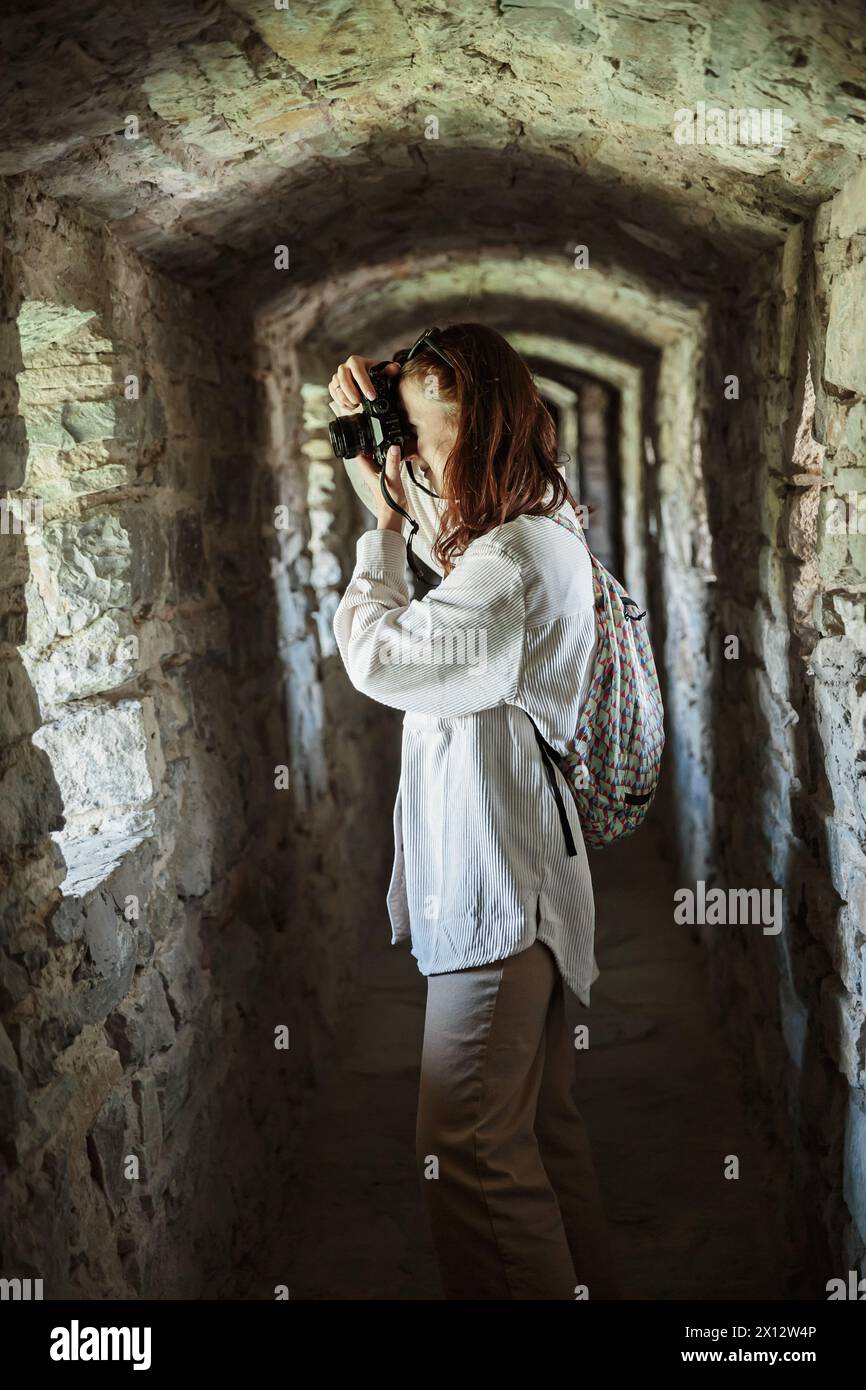 Frau macht Fotos, während sie im Korridor des alten Schlosses steht Stockfoto
