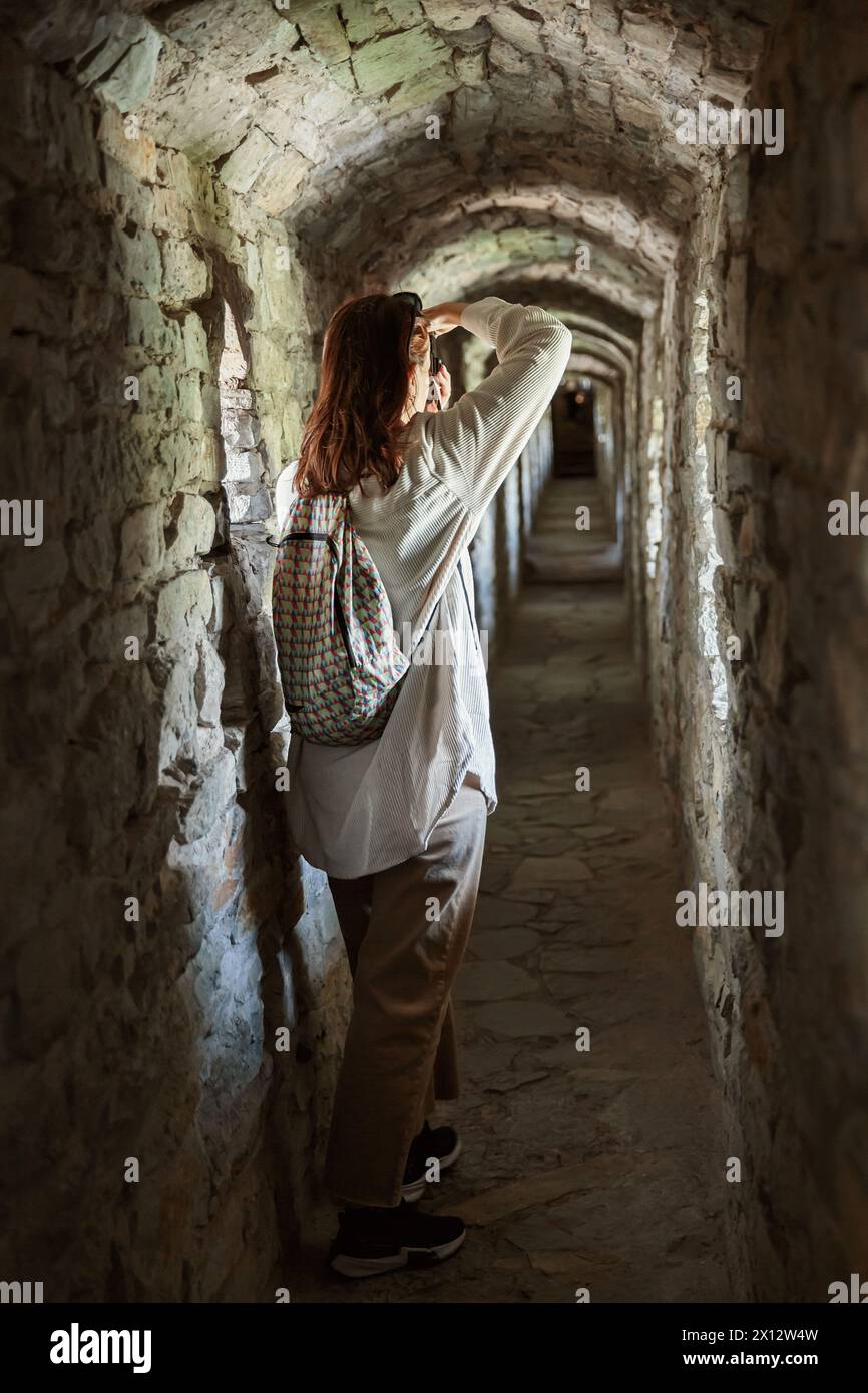 Frau macht Fotos, während sie im Korridor des alten Schlosses steht Stockfoto