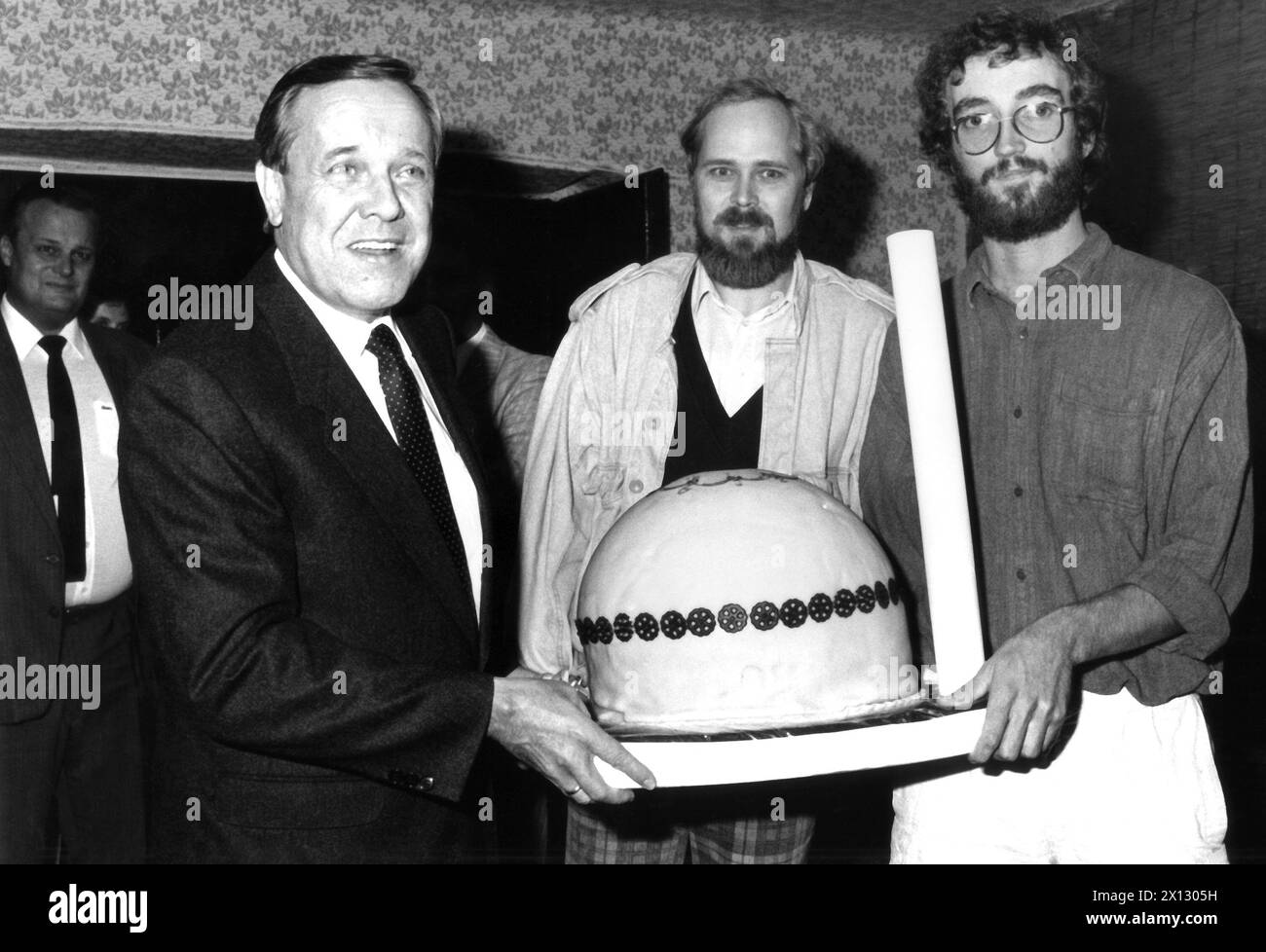 Das Foto vom 24. September 1986 zeigt den deutschen Umweltminister Walter Wallmann (l.), Helmut Hirsch von Greenpeace (c.) und Greenpeace-Sprecher Florian Faber, der einen Kuchen in Form eines Kernkraftwerks hält. Die Greenpeace-Mitglieder waren nicht wellcome auf der Pressekonferenz (die eigentlich für Journalisten stattfand und von Wallmann organisiert wurde). Greenpeace übergab 160,000 Unterschriften, die für alternative Energien plädierten. - 19860924 PD0009 - Rechteinfo: Rechte verwaltet (RM) Stockfoto