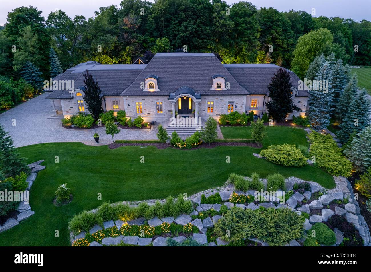Erleben Sie den Reiz luxuriöser, Millionen-Dollar-Häuser in faszinierenden Landschaften der Dämmerung. Erkunden Sie atemberaubende Garten- und Hinterhofdesigns unter der Nacht Stockfoto