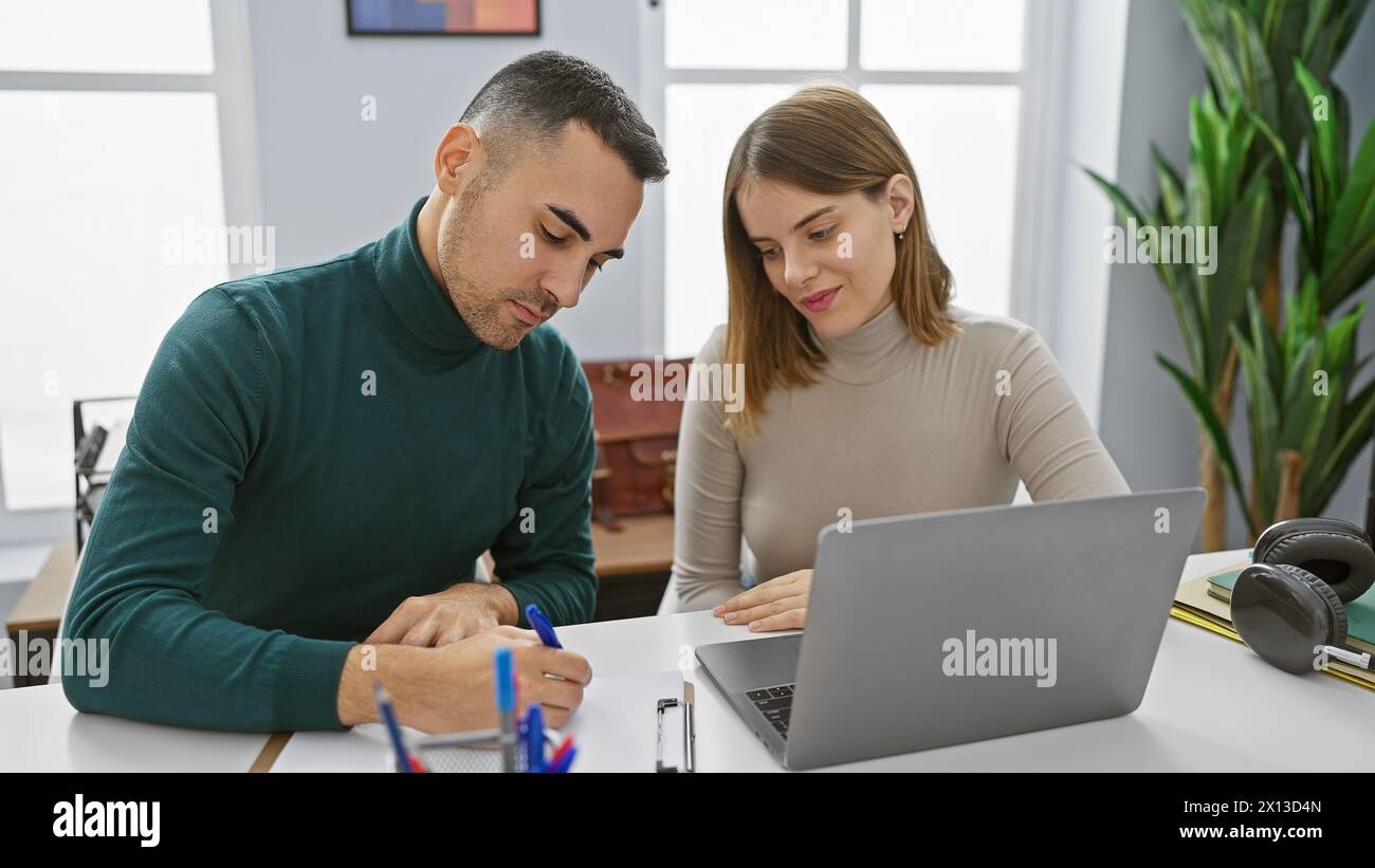 Mann und Frau arbeiten in einem hellen Büro mit Laptop zusammen und machen sich Notizen. Stockfoto