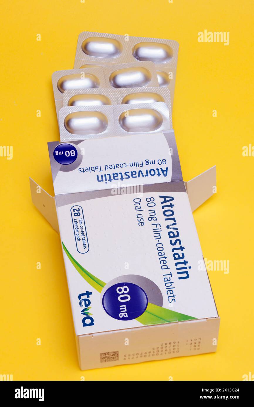 Schachtel mit 28 80 mg Atorvastatin Filmtabletten von Teva zum Einnehmen zur Behandlung von Herzproblemen und zur Senkung des Cholesterinspiegels auf gelbem Hintergrund Stockfoto