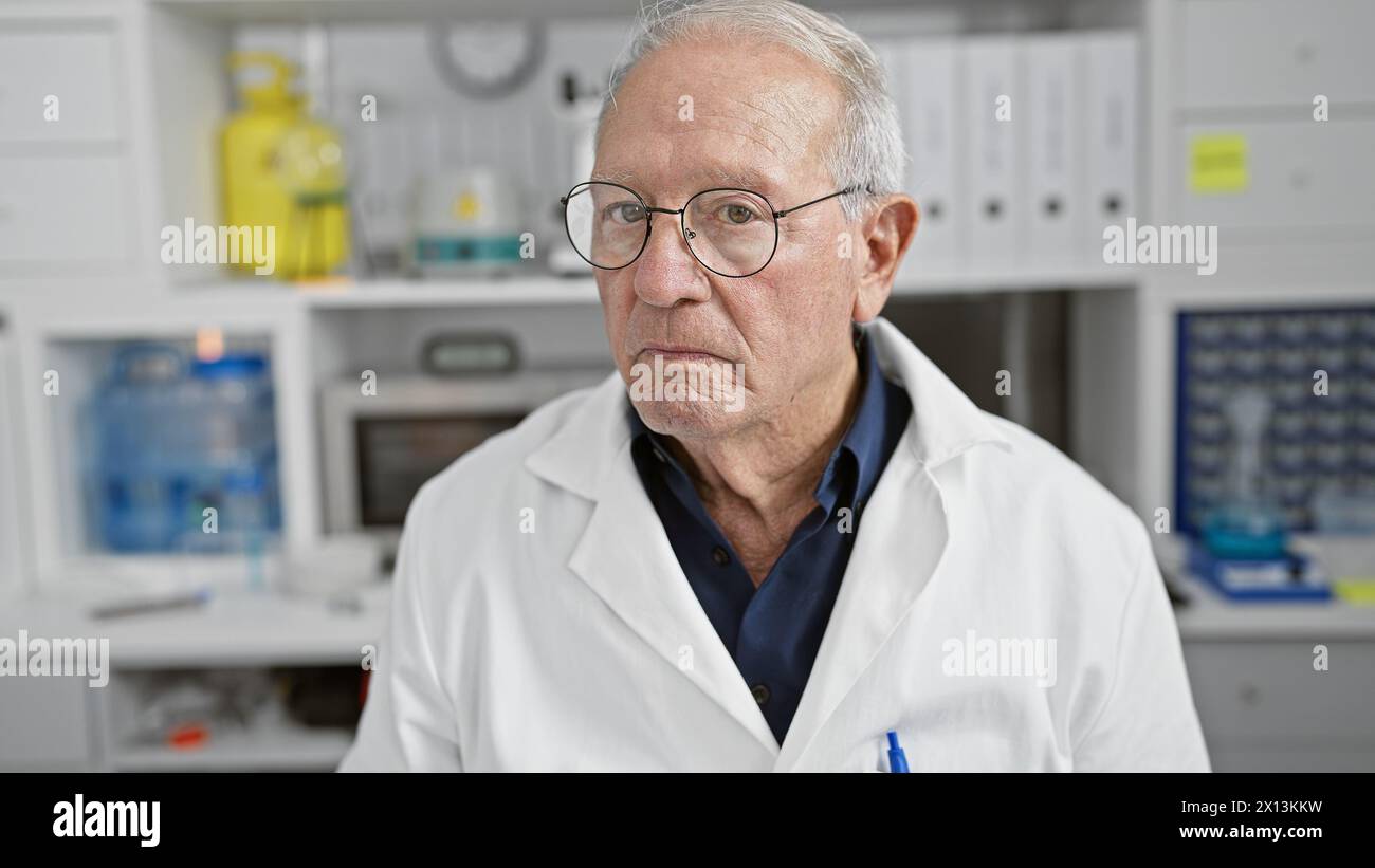 Ernstzunehmender Senior-Mann-Wissenschaftler, der Hingabe für die Medizin zum Ausdruck bringt, Holz tief in der Analyse. Brille tragen, mit der im Labor mühsam gearbeitet wird Stockfoto
