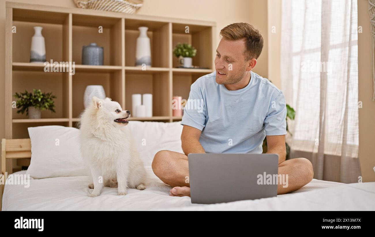 Entspannte Morgenstimmung mit einem glücklichen jungen kaukasier, der auf einem gemütlichen Bett im Schlafzimmer chillt und sich mit seinem Hund und seinem Laptop entspannt. Lächelnder, selbstbewusster Express Stockfoto Entspannte Morgenstimmung mit einem glücklichen jungen kaukasier, der auf einem gemütlichen Bett im Schlafzimmer chillt und sich mit seinem Hund und seinem Laptop entspannt. Lächelnder, selbstbewusster Express Stockfoto