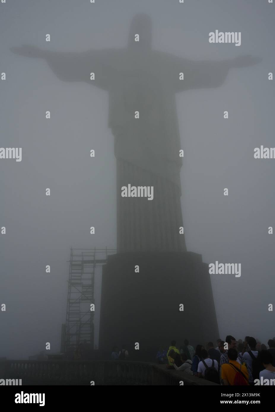 Die Statue von Christus dem Erlöser umgeben von Nebel mit Touristen, die nach oben schauen. Stockfoto