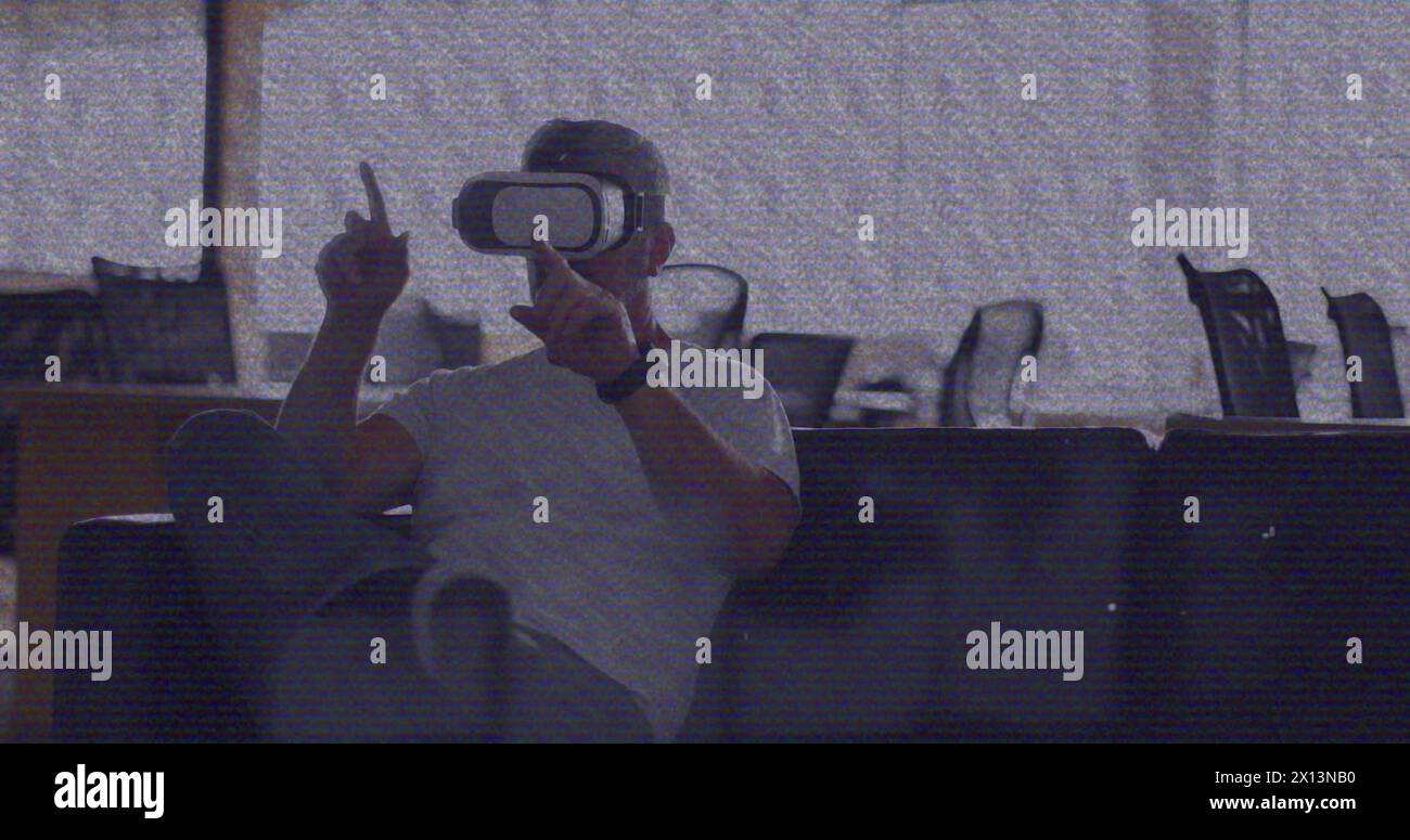 Bild eines vhs-Glitcheffekts über einem kaukasischen Mann, der vr-Headset im Büro trägt Stockfoto