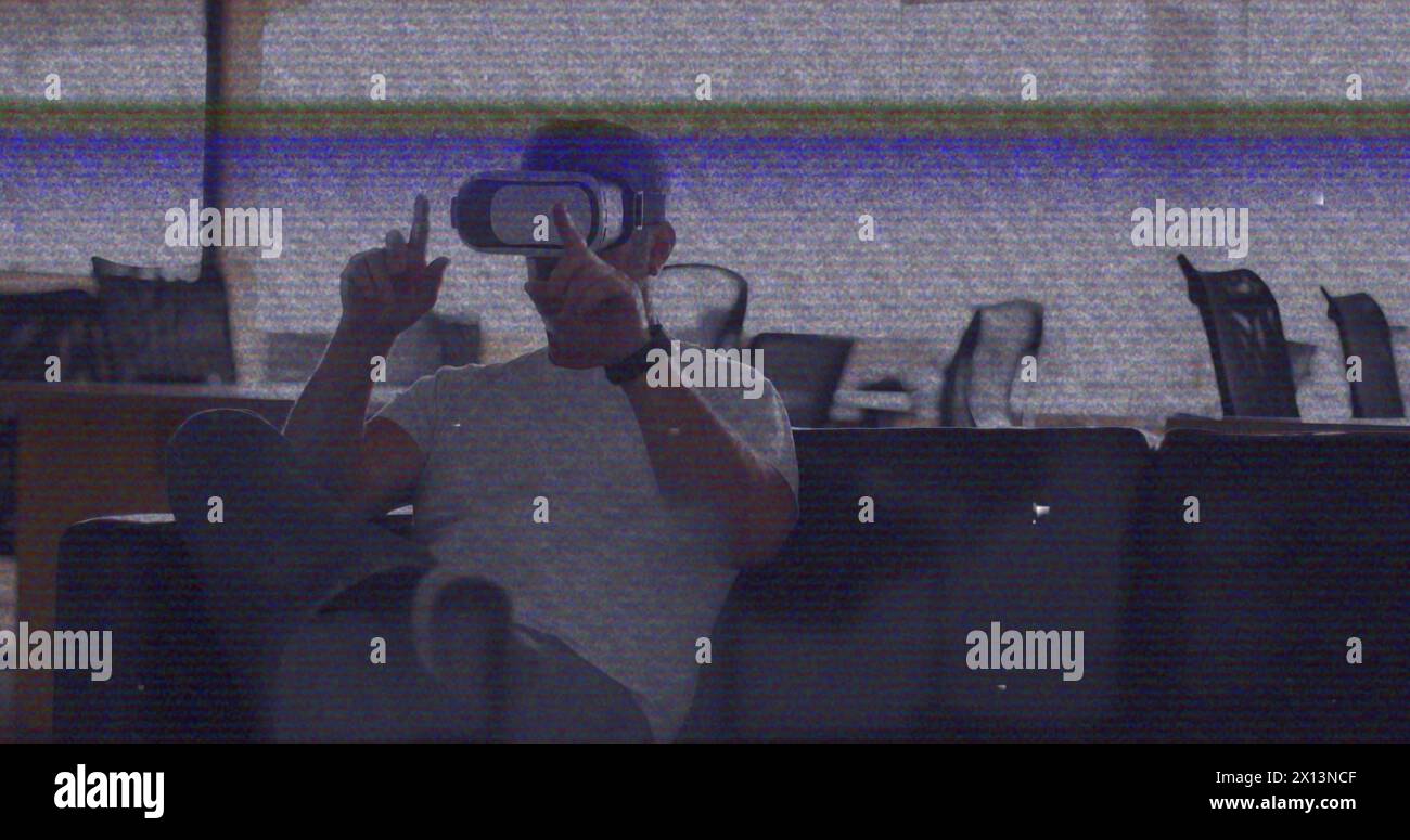 Bild eines vhs-Glitcheffekts über einem kaukasischen Mann, der vr-Headset im Büro trägt Stockfoto