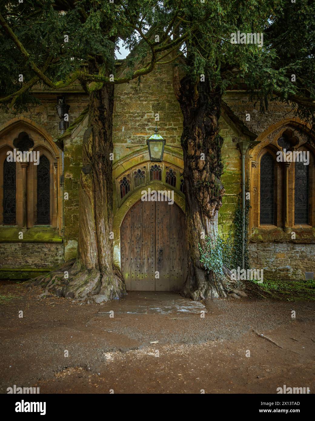 Die Tolkien-Tür an der St. Edwards-Kirche, flankiert von zwei alten Ulmenbäumen. Historischer Friedhof in Stow on the Wold, den Cotswolds, England. Stockfoto