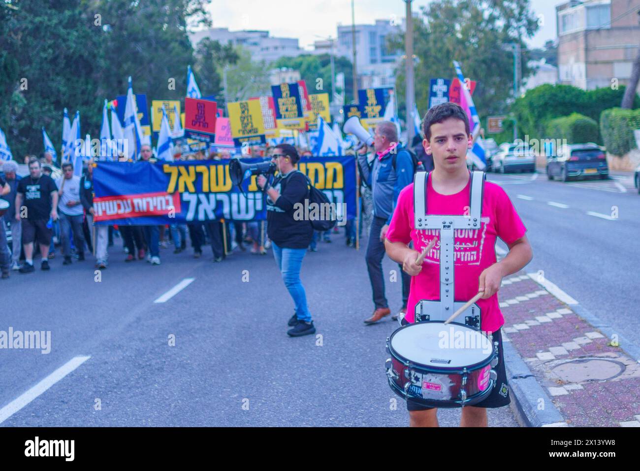 Haifa, Israel - 13. April 2024: Menschen nehmen an einem protestmarsch mit verschiedenen Zeichen und Flaggen gegen die Regierung Teil und rufen zu Neuwahlen auf. Stockfoto