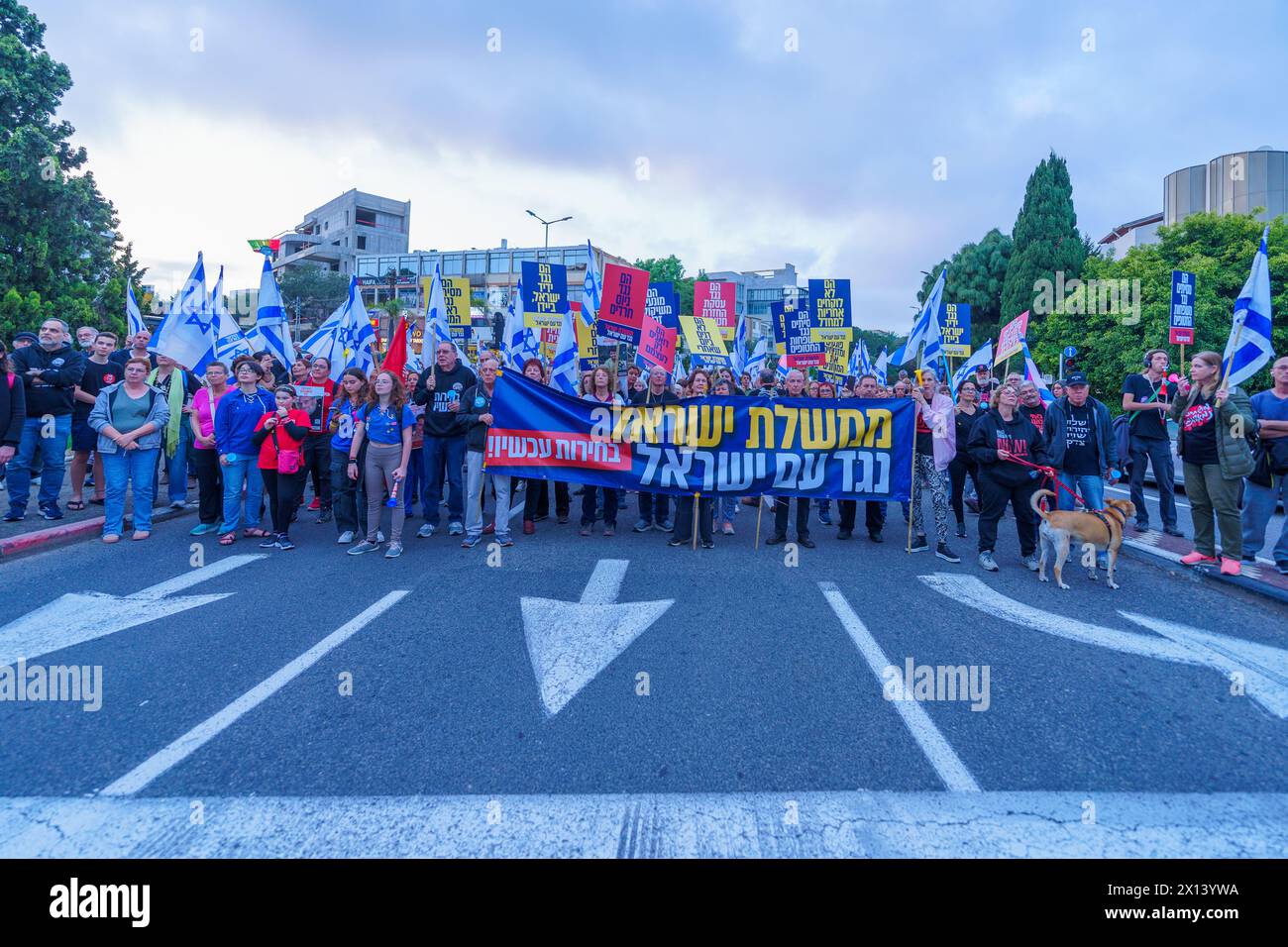 Haifa, Israel - 13. April 2024: Menschen nehmen an einem protestmarsch mit verschiedenen Zeichen und Flaggen gegen die Regierung Teil und rufen zu Neuwahlen auf. Stockfoto