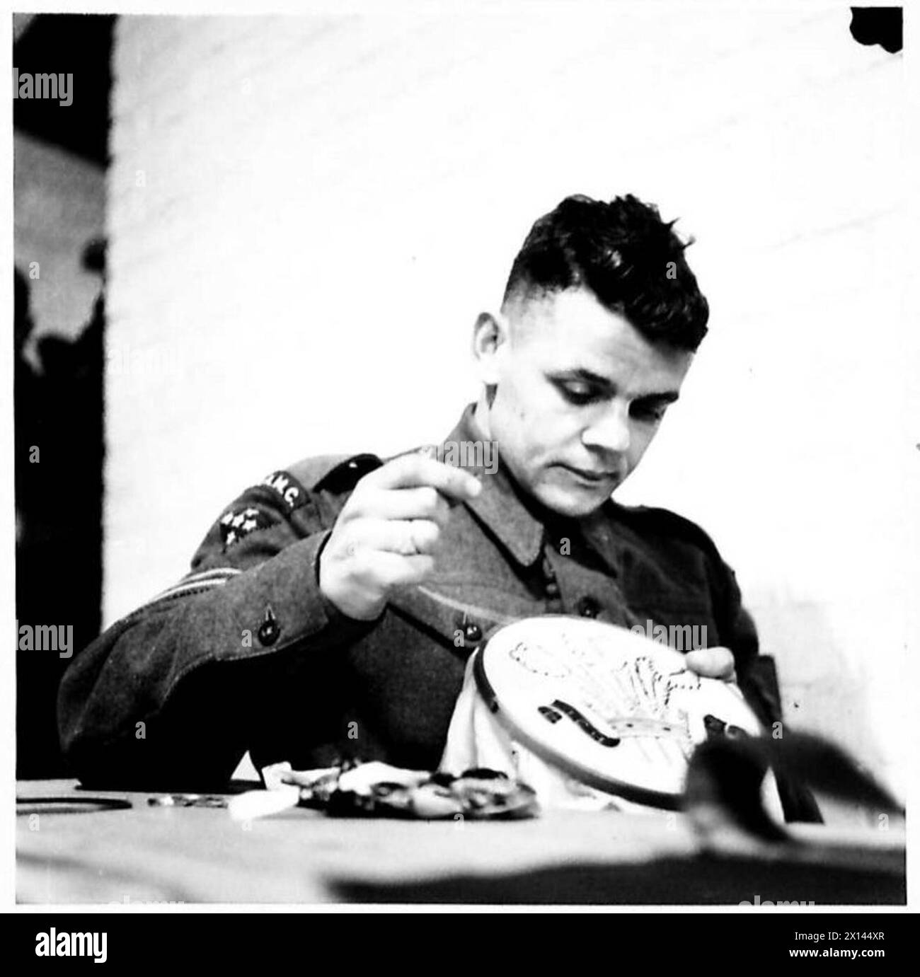 KRANKENHAUSPERSONAL UND PAITENTS MACHEN WEIHNACHTSGESCHENKE - Corporal F.S. Hawkins, R.A.M.C. stickt das Welch-Abzeichen British Army Stockfoto