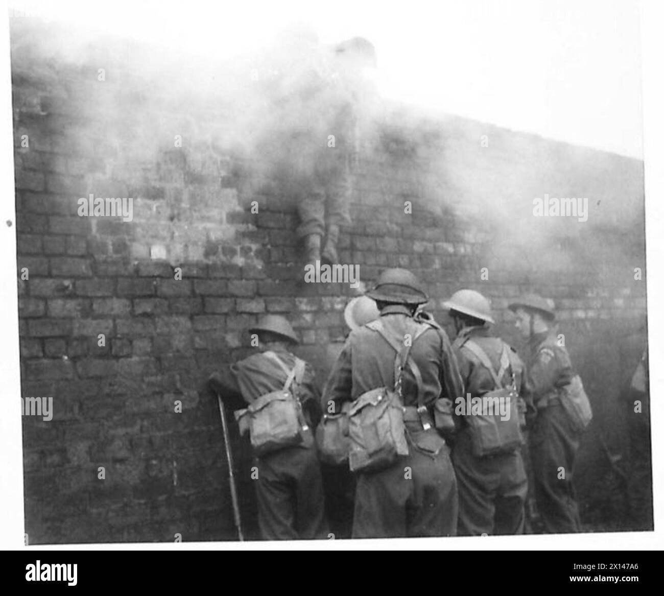 Die Heimwächter klettern mit Rauchschirmen während einer Demonstration von Generalmajor Johnson an der Glasgow Home Guard Fighting School auf eine Mauer. Stockfoto