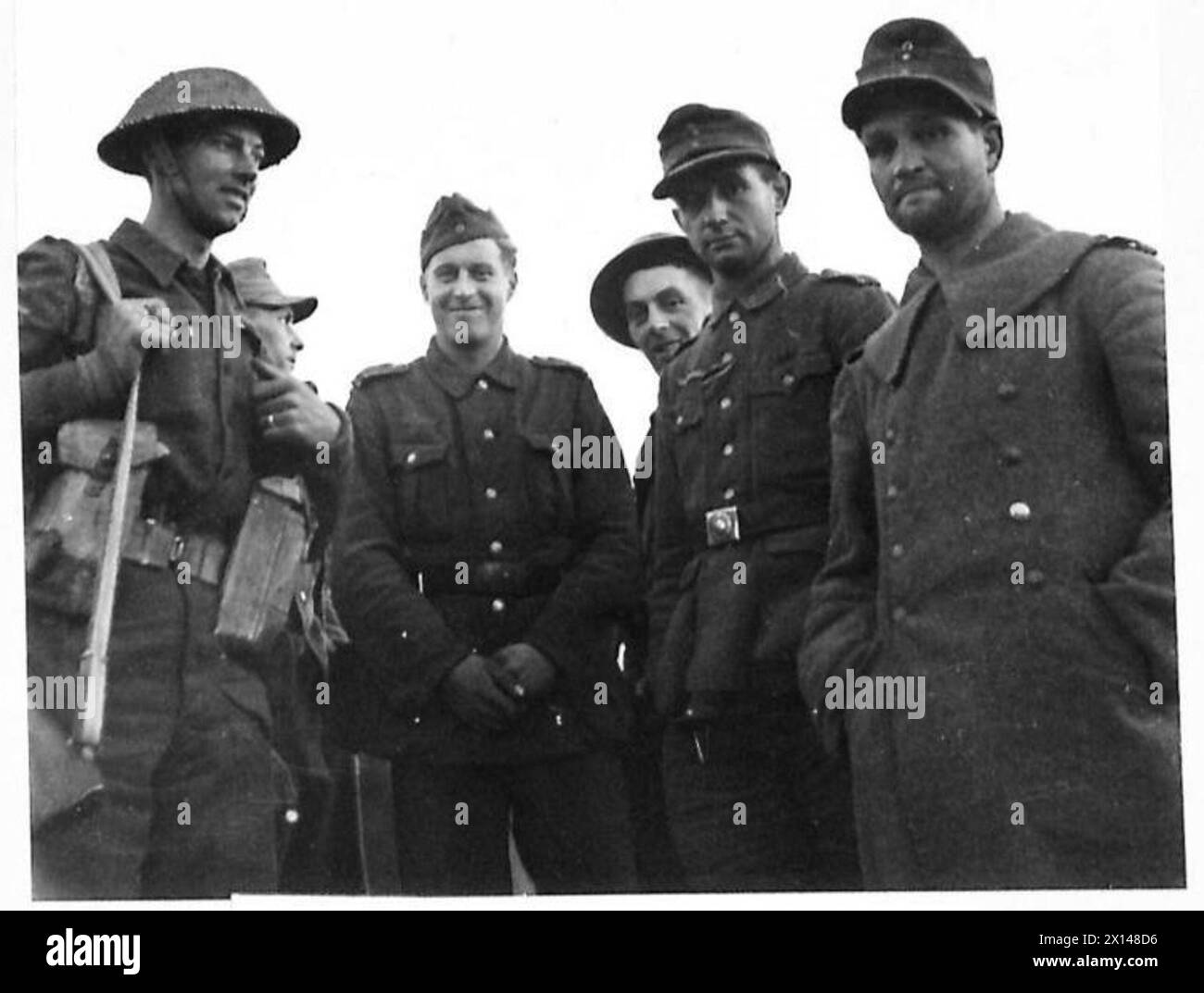 Gefangene, die in den frühen Phasen der Landung der Alliierten südlich von Rom gefangen genommen wurden, werden am Strand von britischen Armeepersonal gefangen gehalten. Stockfoto