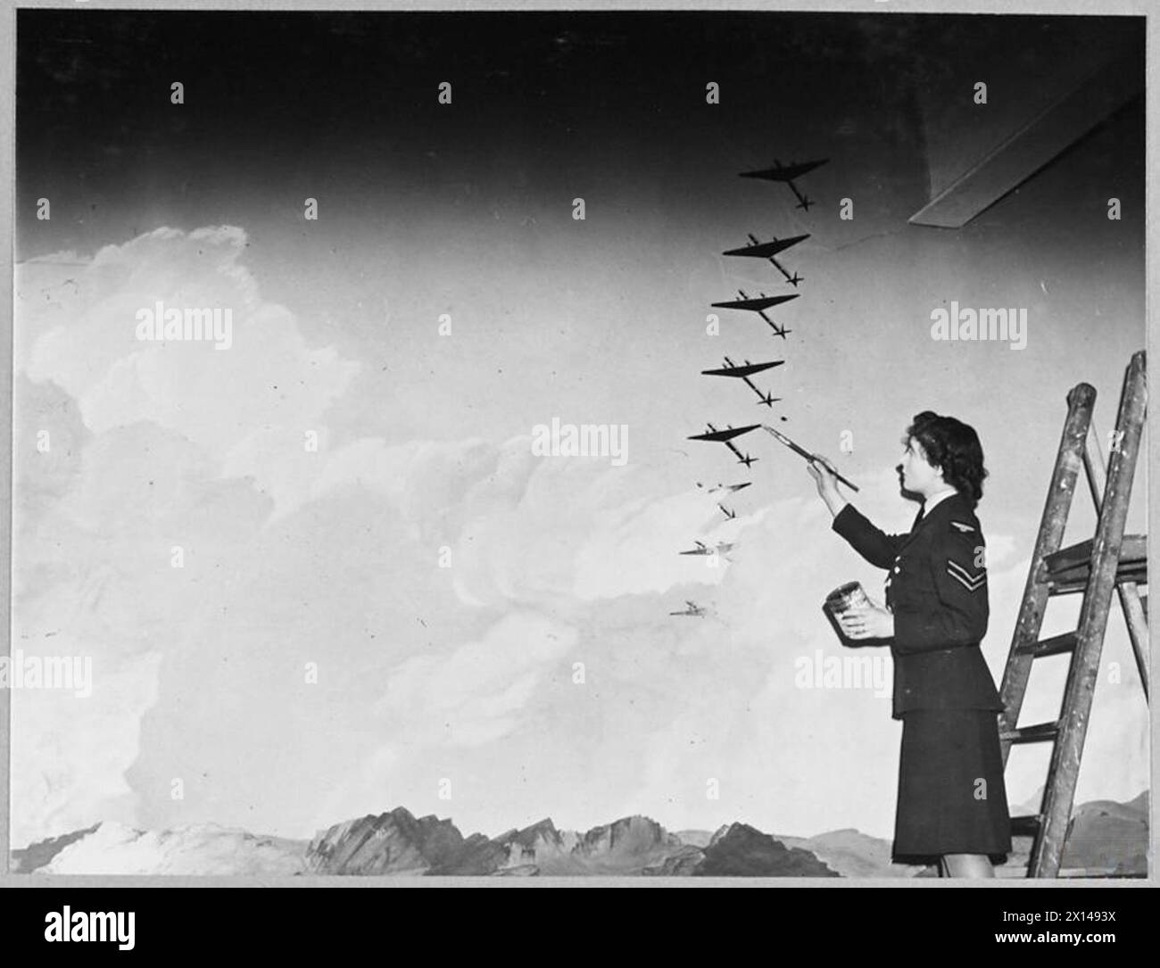 Foto mit RAF- und WAAF-Künstlern, die ein Wandbild mit anmutigen Flugzeugen kreieren, die in Formation durch Wolken fliegen. Stockfoto